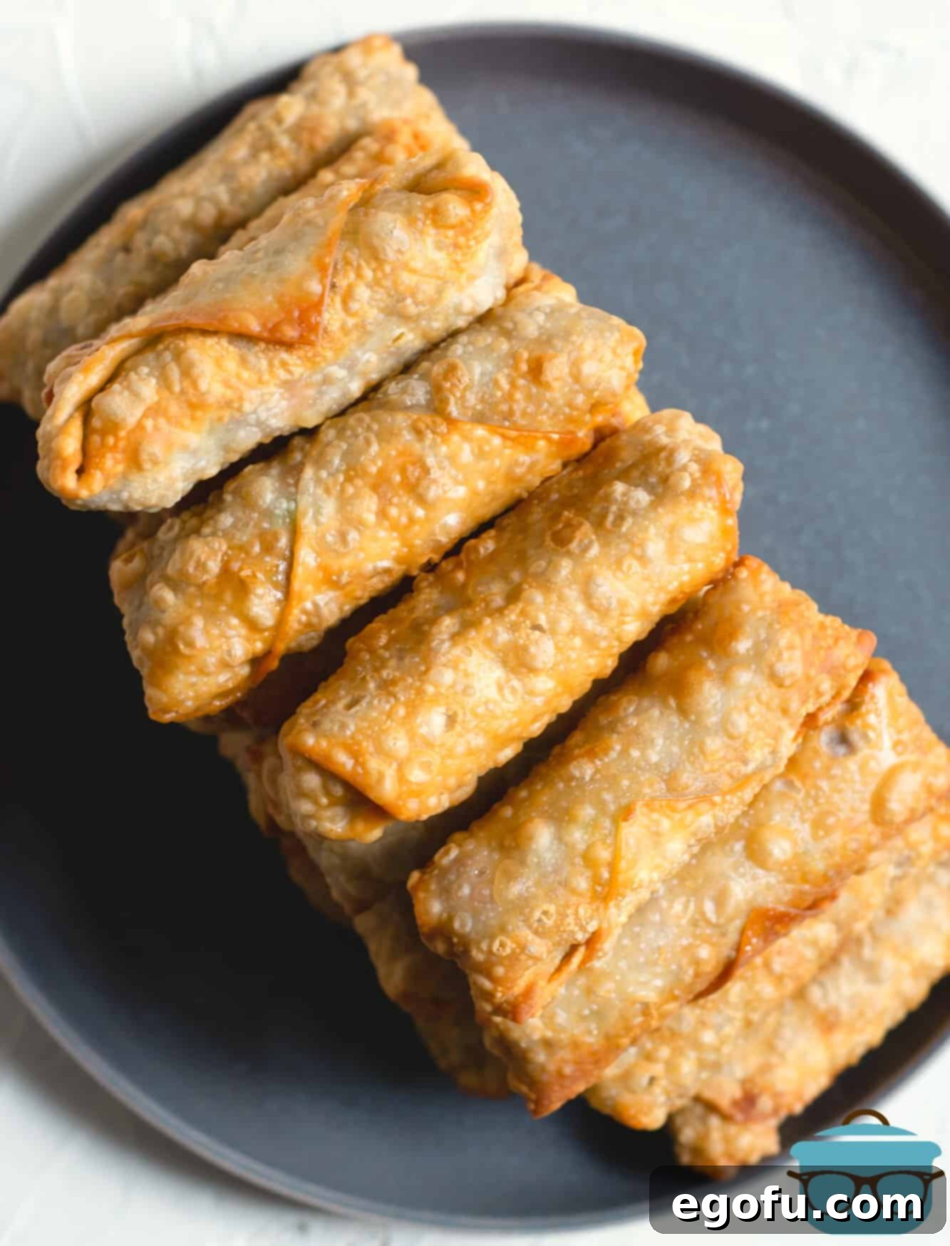 Crispy Cheeseburger Rolls 10 Fried cheeseburger egg rolls stacked high on a plate, showcasing their golden crispiness.