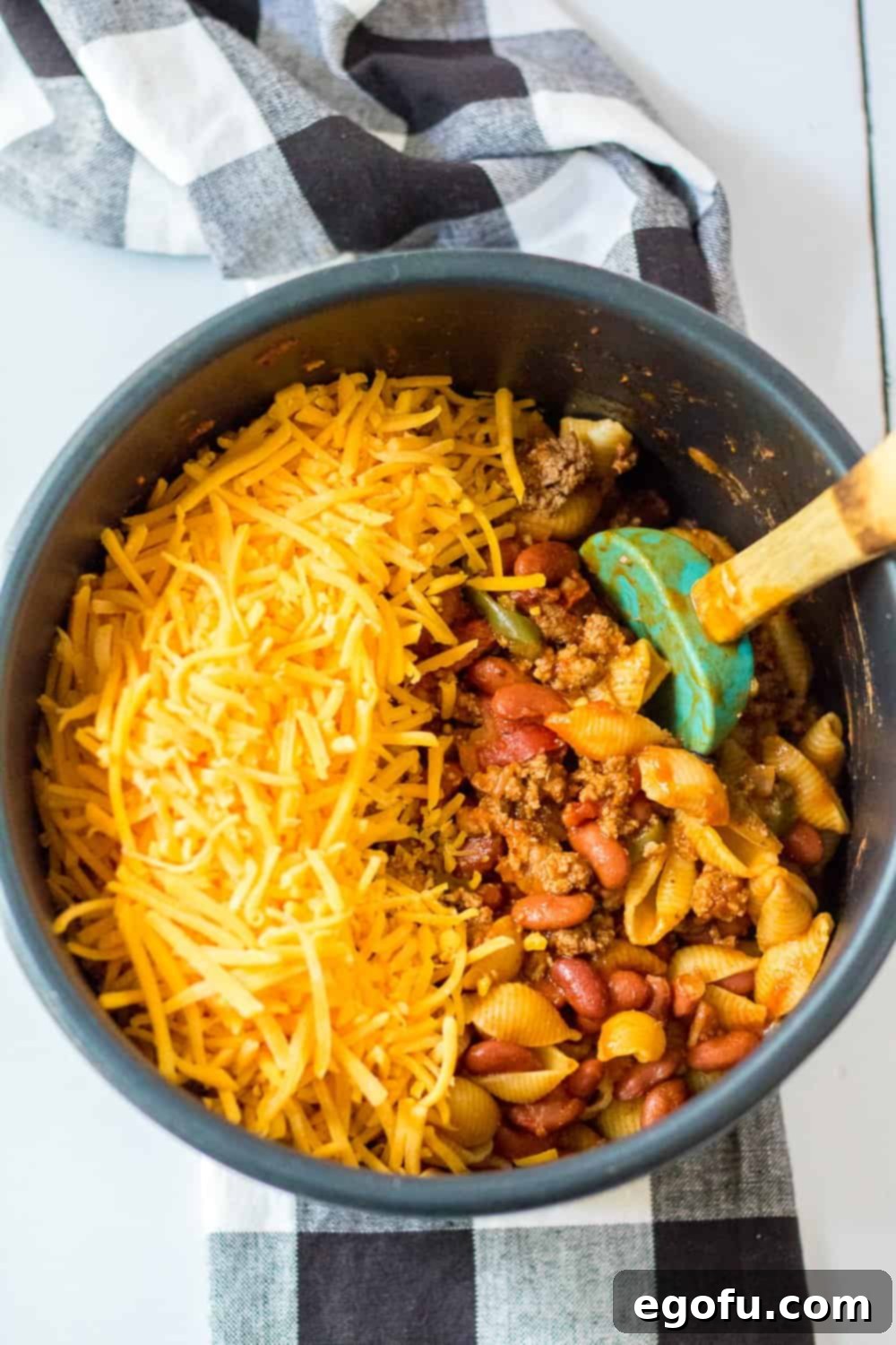 shredded cheddar cheese added to fully cooked taco pasta in the instant pot pressure cooker insert bowl.
