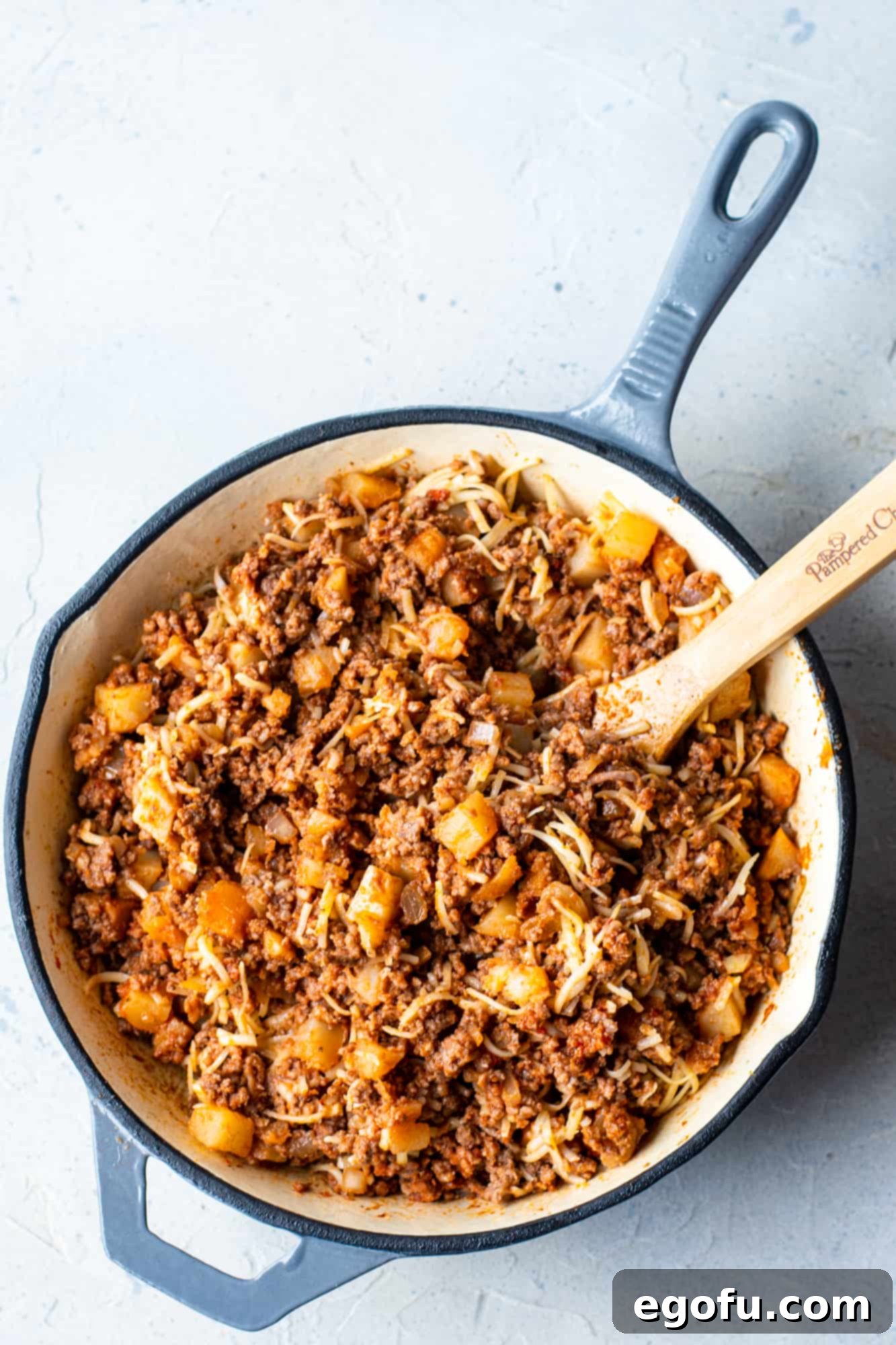 Cooked ground beef mixed with cheese and diced potatoes, ready for hand pie assembly.