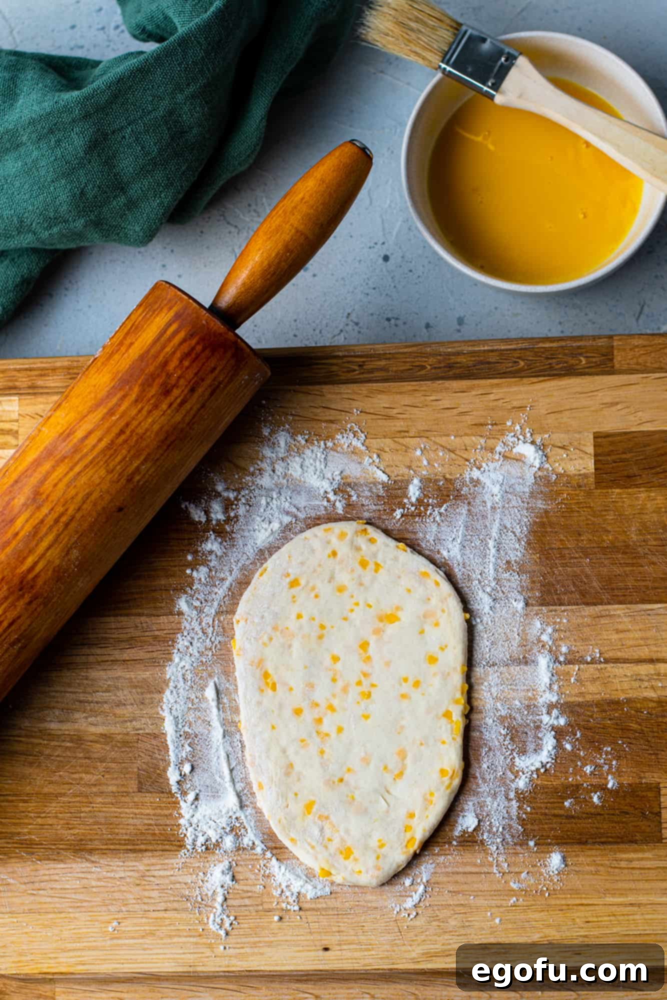 Rolling out a refrigerated biscuit on a wooden cutting board with a rolling pin.