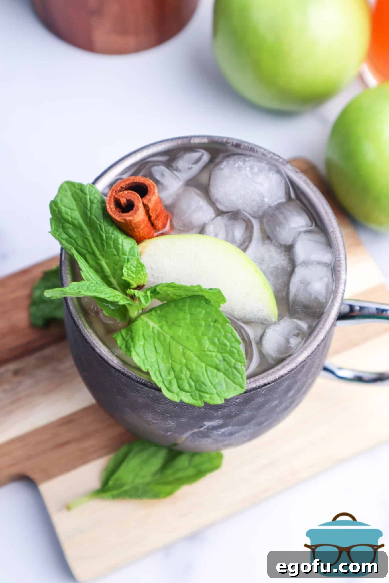 Fireball Apple Cider Moscow Mule, shown closeup from the top and garnished with a slice of green apple and a cinnamon stick.