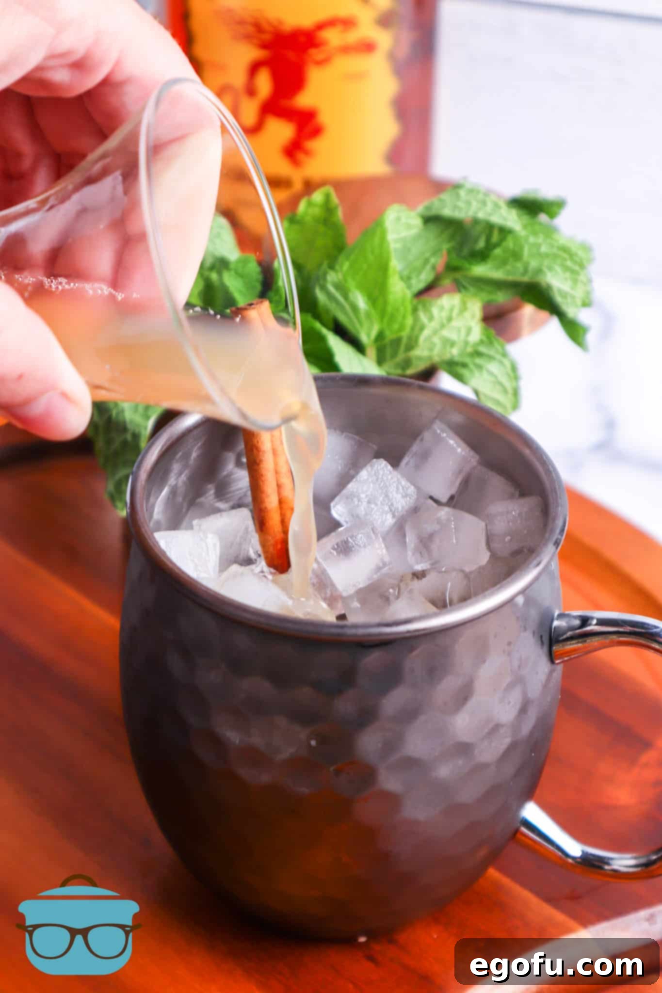 apple cider being poured into a silver Moscow Mule mug.