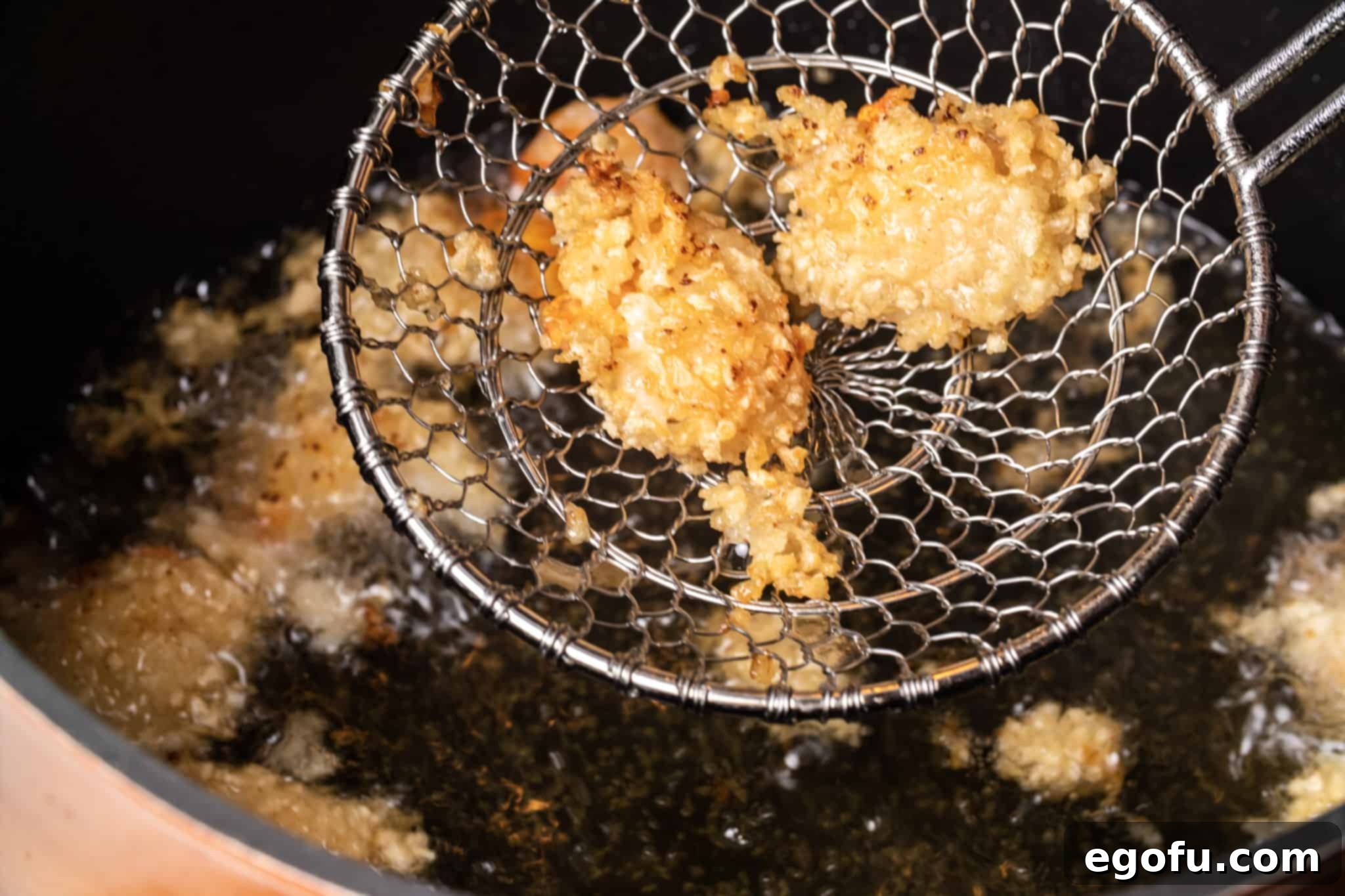 Succulent oil-fried shrimp beautifully cooking in a large pot filled with hot oil, achieving a perfect golden crisp.