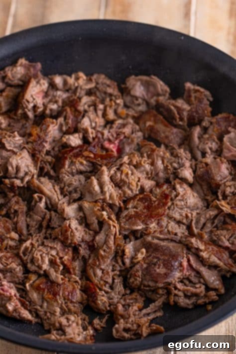 Cooked preshaved ribeye in a skillet.