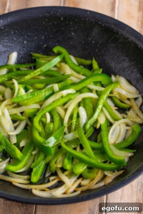 Cooked onions and peppers in a skillet.