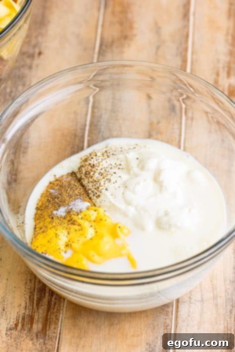 A mixing bowl with sour cream, soup, milk, and pepper.