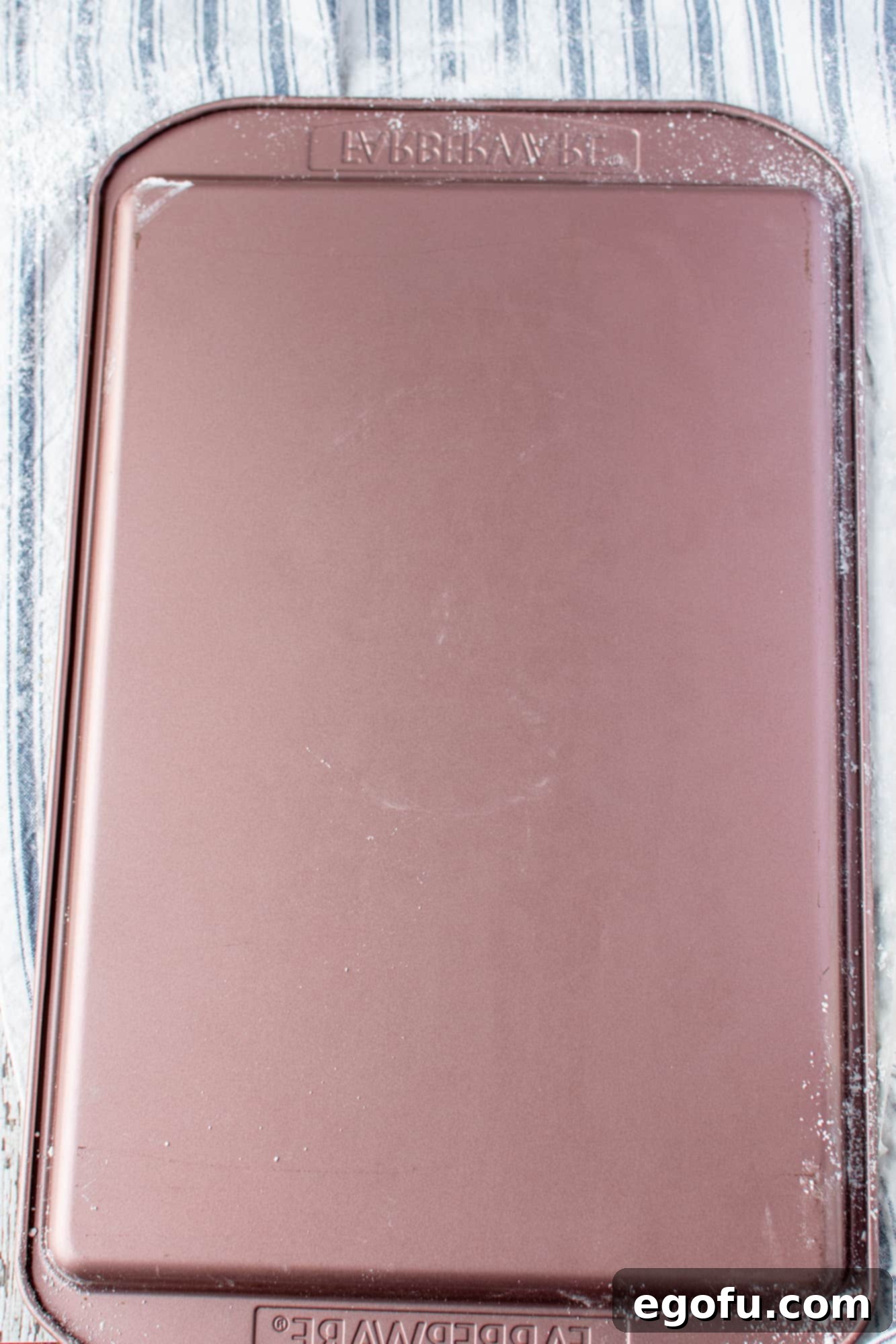 A warm pumpkin cake being carefully inverted from the baking pan onto a powdered sugar-dusted kitchen towel.