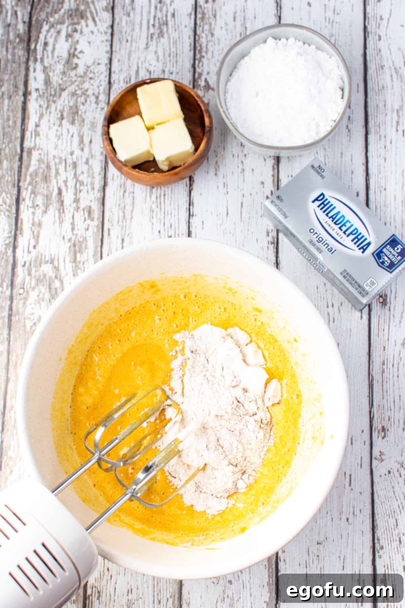 Dry flour mixture being gently folded into the pumpkin and egg batter in a large mixing bowl, avoiding overmixing.