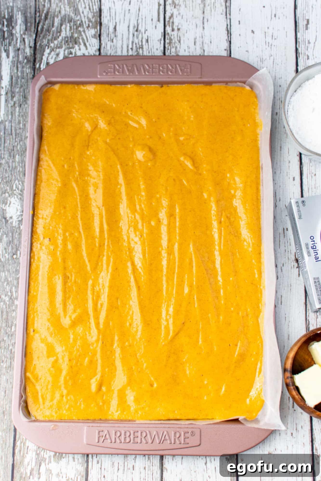 Pumpkin cake batter evenly spread into a 10x15-inch jelly roll baking pan, ready for the oven.