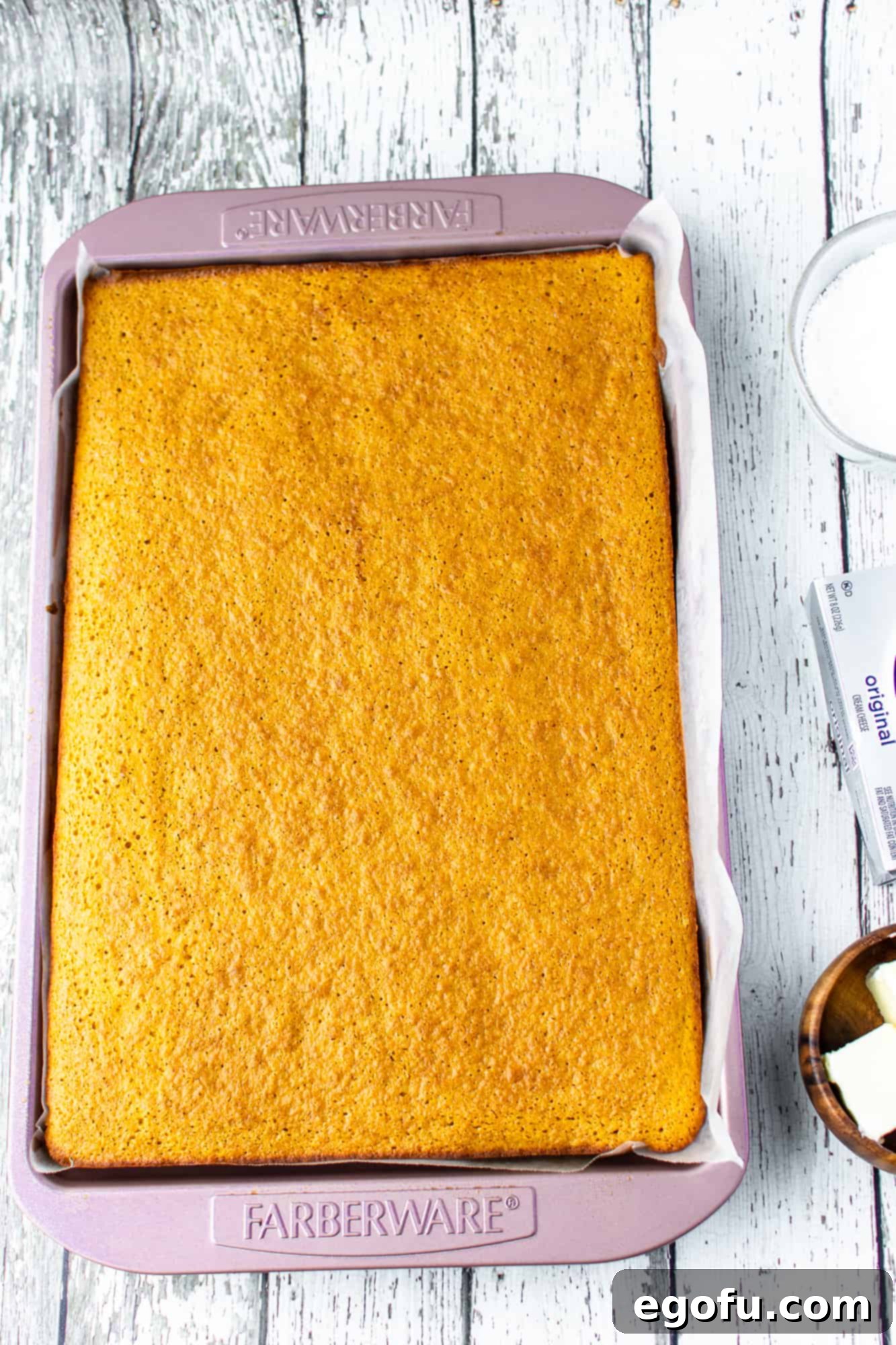 A freshly baked pumpkin cake, golden brown and perfectly risen, resting in its jelly roll pan.