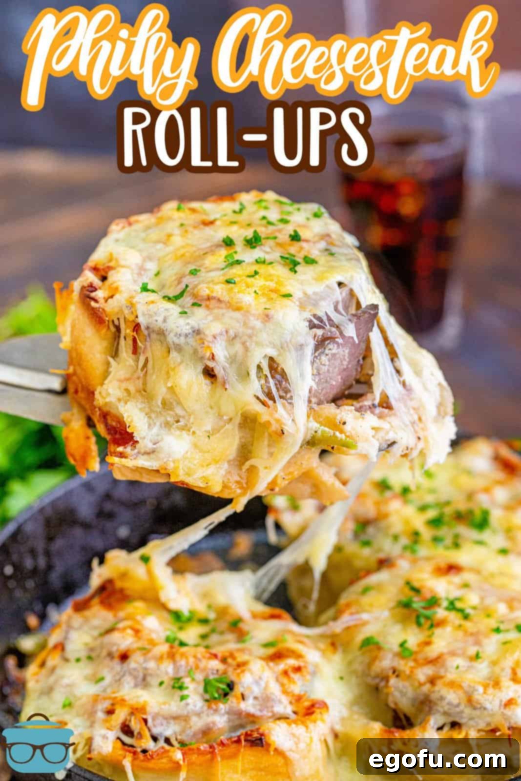 Philly Cheesesteak Pinwheels 4 a spatula holding up a piece of cheesesteak rollup over cast iron skillet.