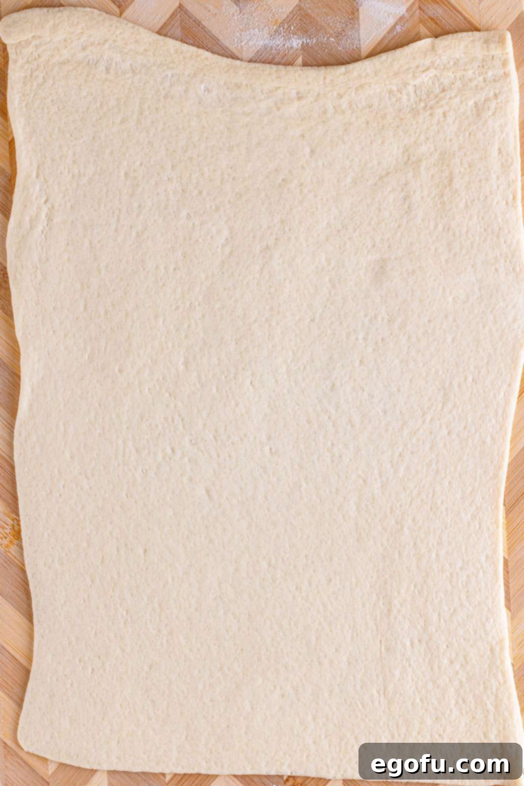 Philly Cheesesteak Pinwheels 6 pizza dough rolled out flat on a large cutting board.