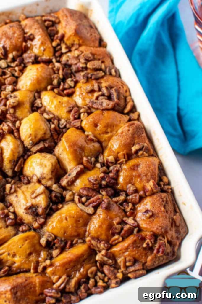 Fully baked easy French toast casserole recipe with a golden-brown pecan topping, served in a cream baking dish with a blue napkin.