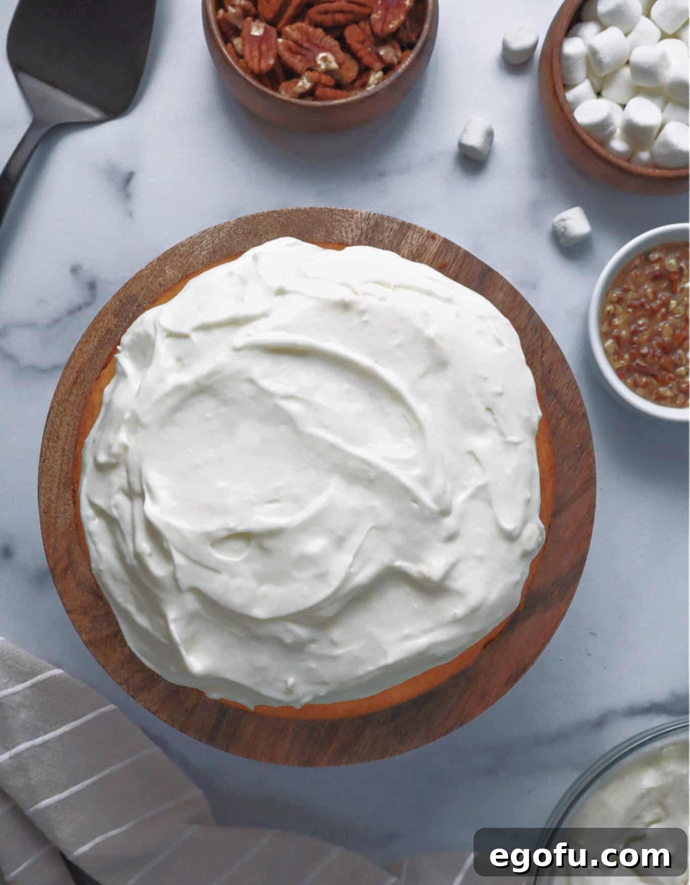 Effortless Sweet Potato Layer Cake 7 A generous layer of creamy white marshmallow frosting spread smoothly over the first layer of sweet potato cake, creating a perfect base for the second cake layer.