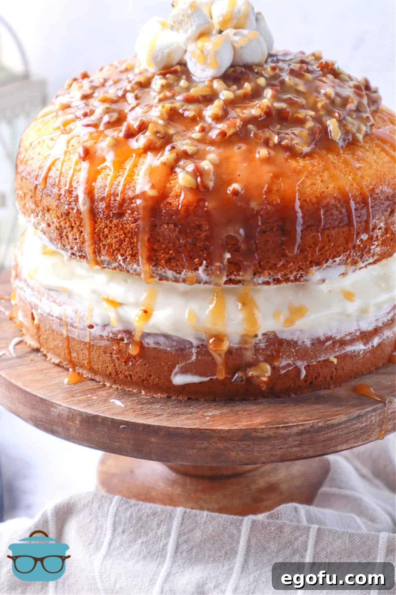 Effortless Sweet Potato Layer Cake 8 The fully assembled Loaded Sweet Potato Layer Cake on a wooden pedestal, with glistening candied pecan glaze generously drizzling down its sides, highlighting its rich textures and inviting aroma.