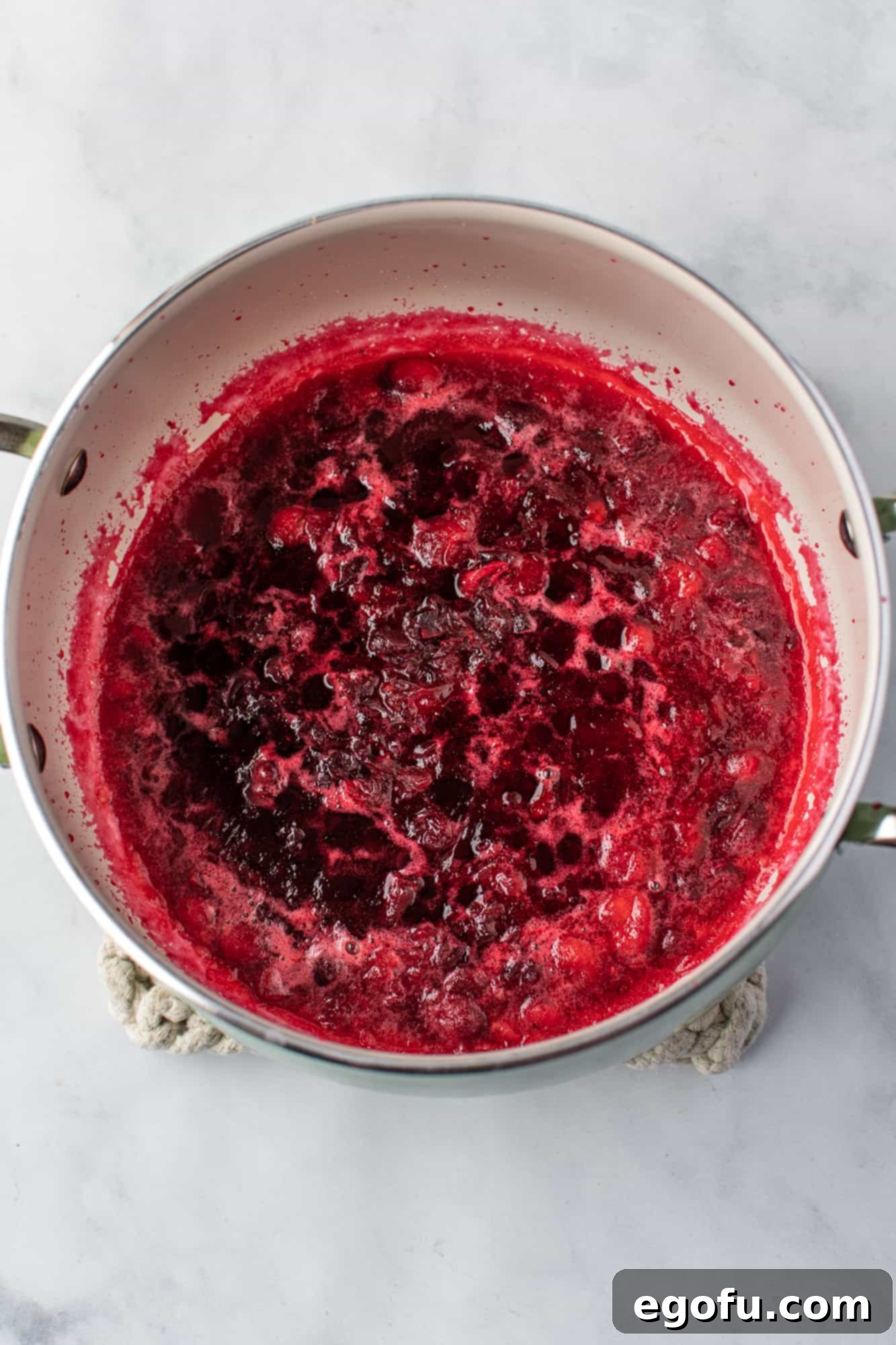 Effortless Cranberry Sauce 6 crushed cranberries in a silver sauce pan.