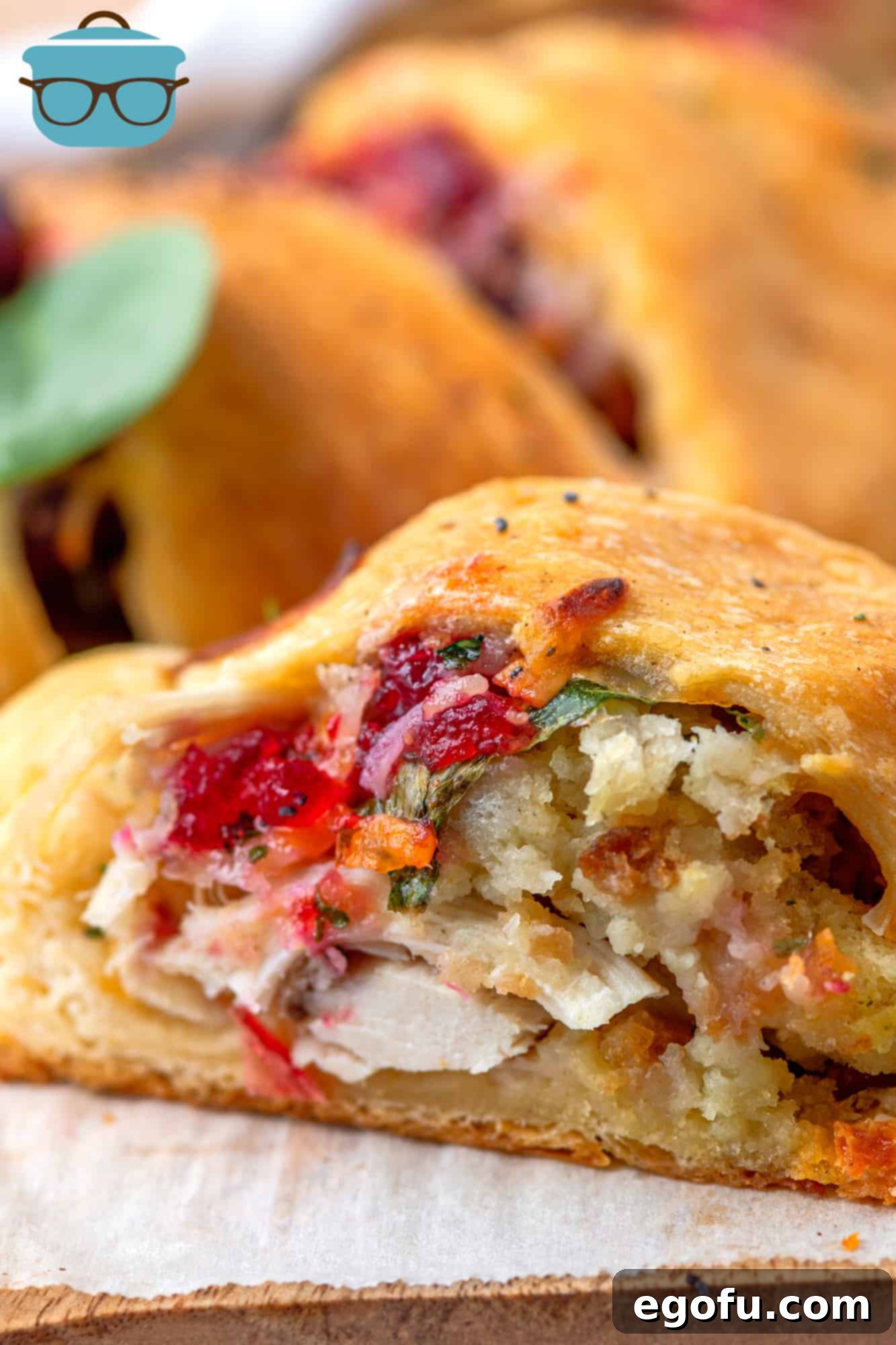 Festive Turkey Stuffing Crescent Bake 14 An inside view of a sliced Turkey and Stuffing Crescent Ring, revealing the flavorful layers of turkey, stuffing, spinach, cranberry sauce, and melted cheese, all within the flaky crescent dough.