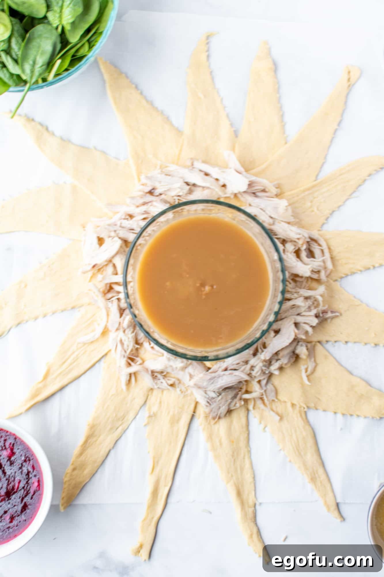 Festive Turkey Stuffing Crescent Bake 6 Shredded cooked turkey being carefully placed on top of the crescent rolls, forming the first layer of filling in the crescent ring.