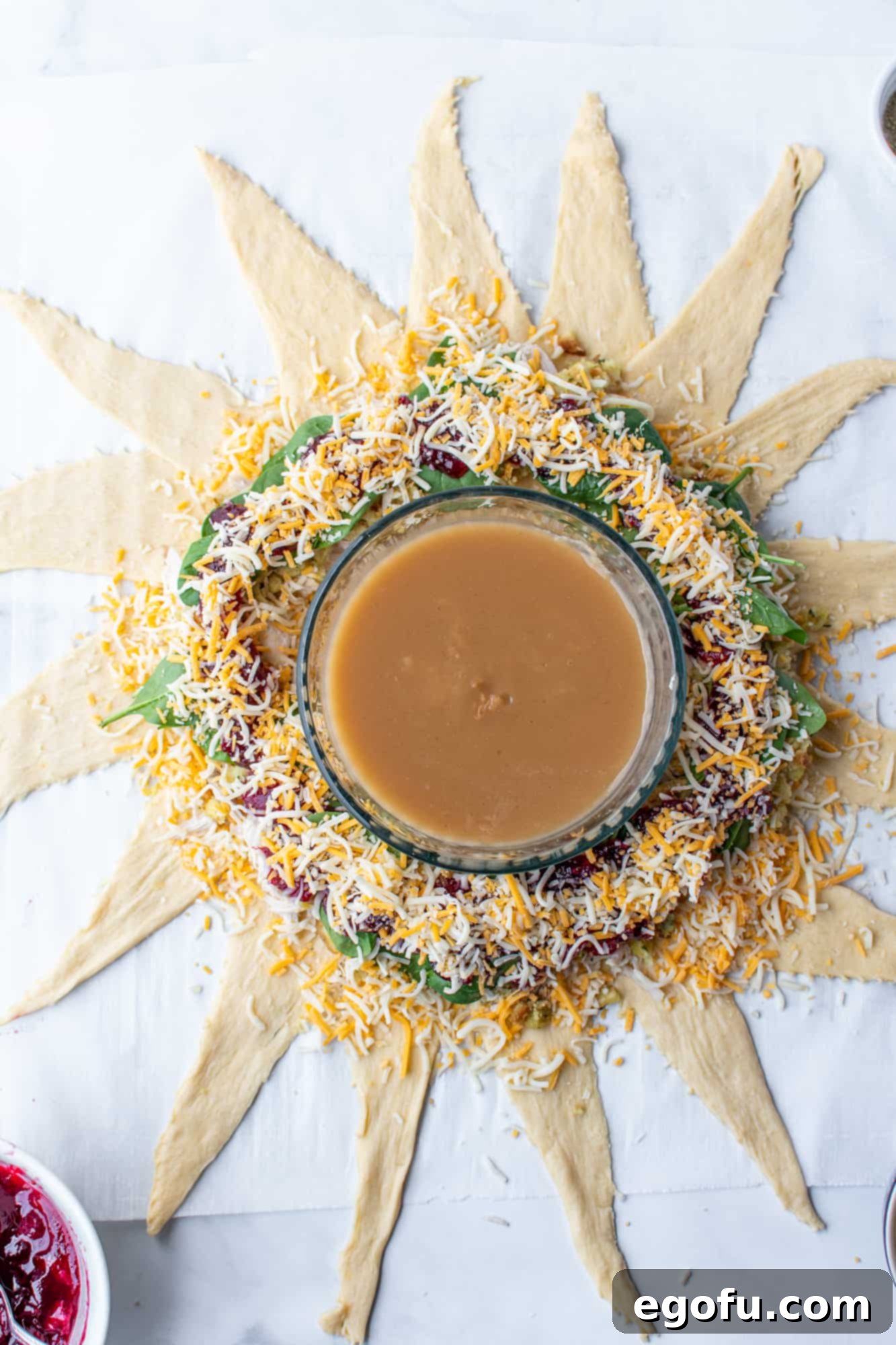 Festive Turkey Stuffing Crescent Bake 10 Shredded Monterey Jack cheese generously sprinkled over the cranberry sauce layer, preparing the crescent ring for baking.