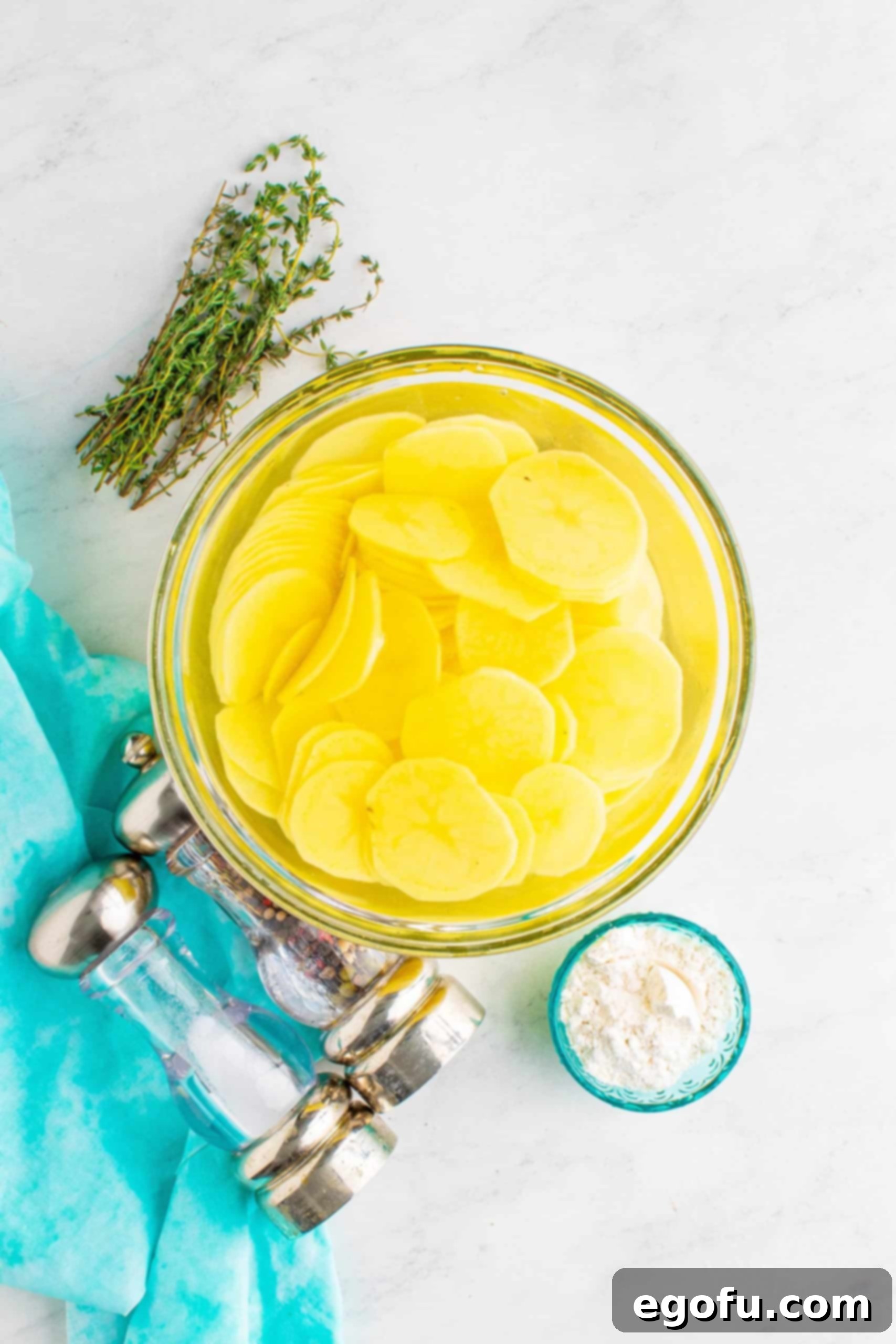 sliced potatoes soaking in cool water in a clear bowl.