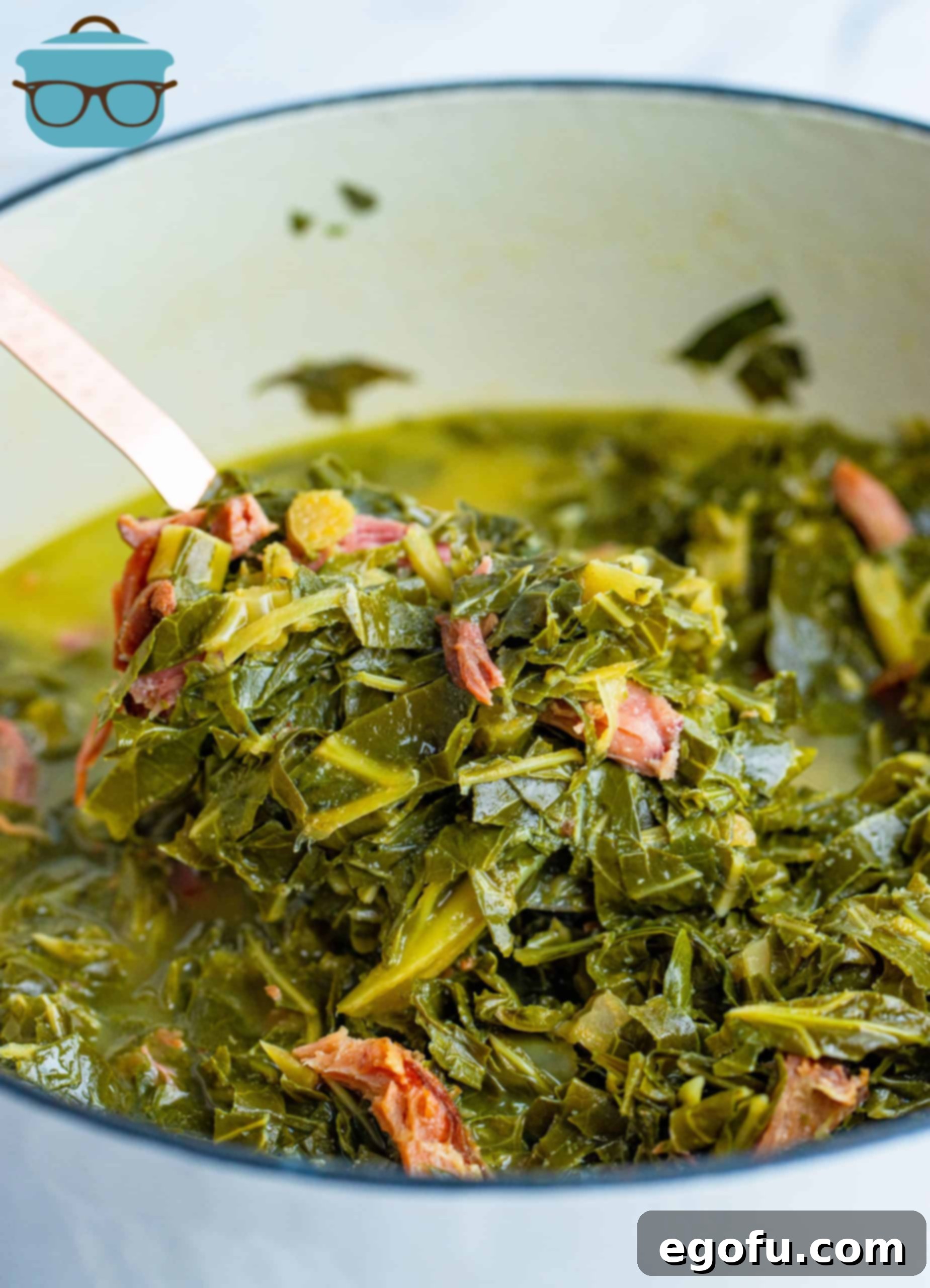 Fully cooked collard greens and ham in a white stock pot, ready to be served as a classic Southern dish.