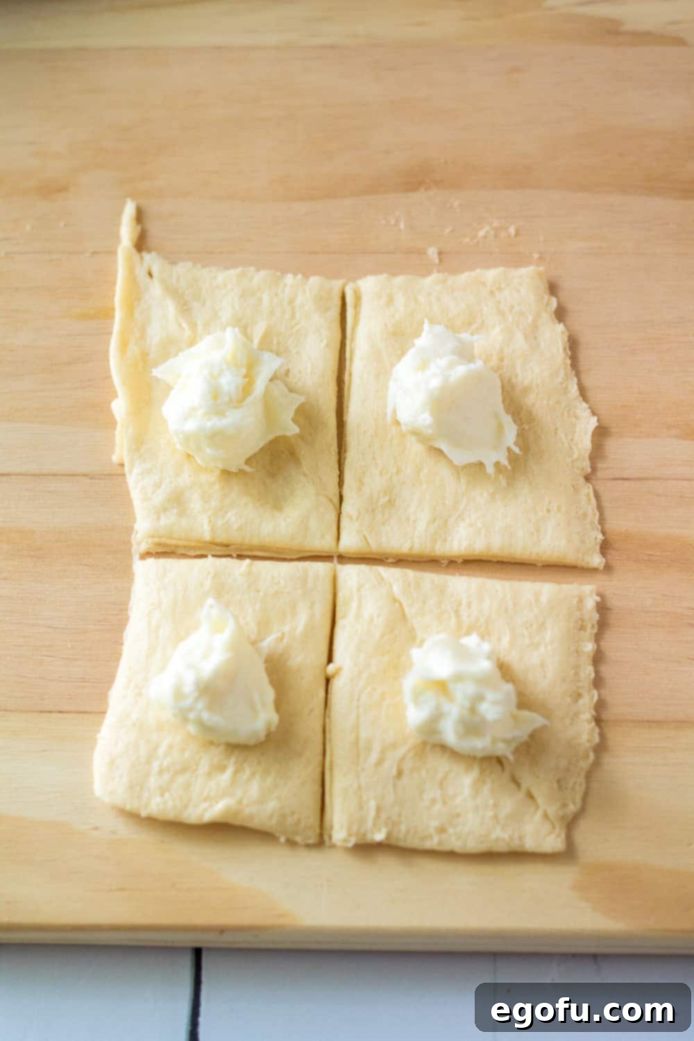 cream cheese filling scooped into crescent roll dough squares.