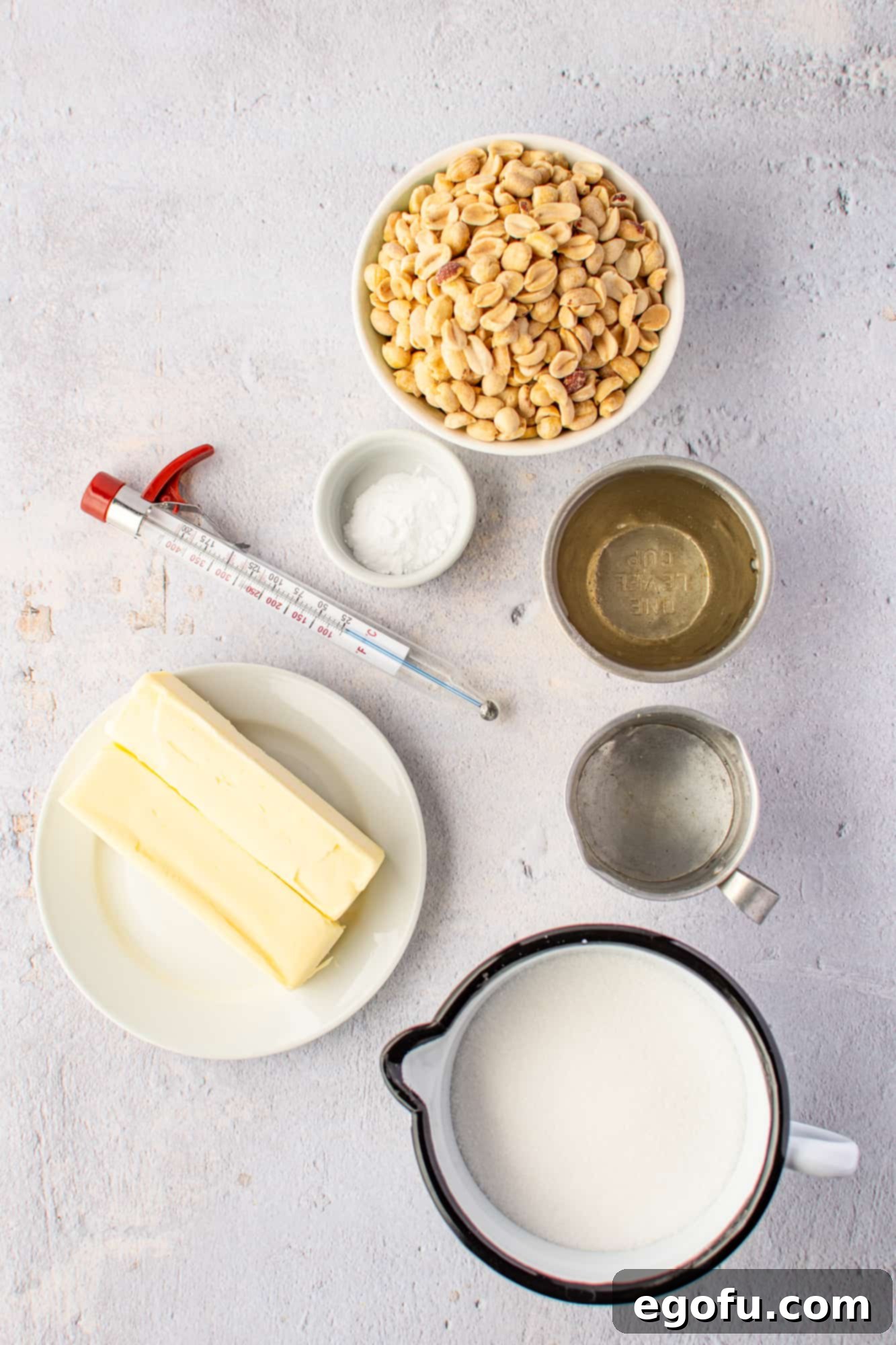Golden Crunch Peanut Brittle 4 A collection of ingredients laid out: sugar, light corn syrup, water, salt, unsalted butter, unsalted dry roasted peanuts, and baking soda.