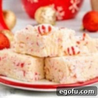A delicious block of Candy Cane Peppermint Fudge, showcasing its smooth texture and festive candy cane pieces.