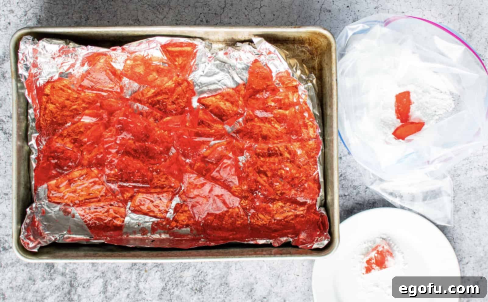 A sheet of broken Apple Cinnamon Rock Candy resting in a baking pan lined with foil, showcasing its fragmented form after cooling.