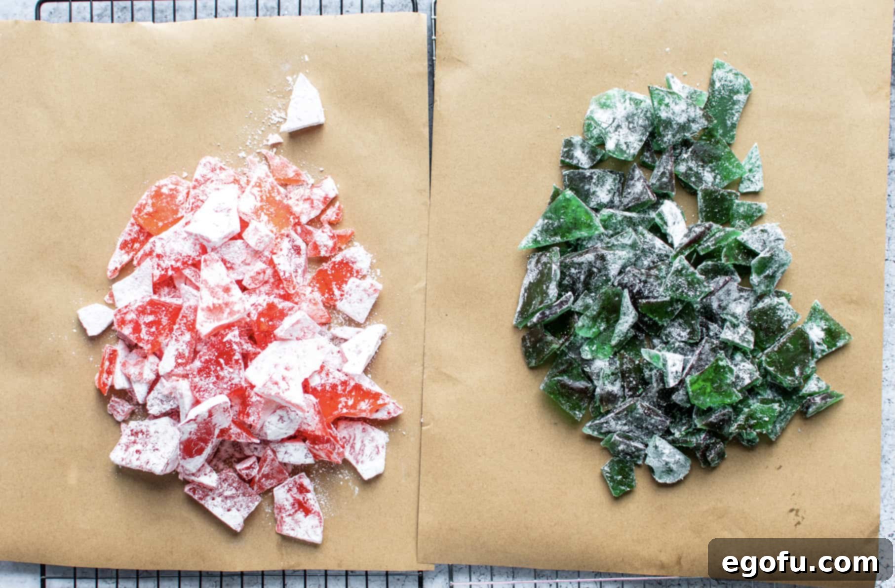 Broken pieces of rock candy, perfectly coated in powdered sugar, are scattered on parchment paper, ready for storage or serving.