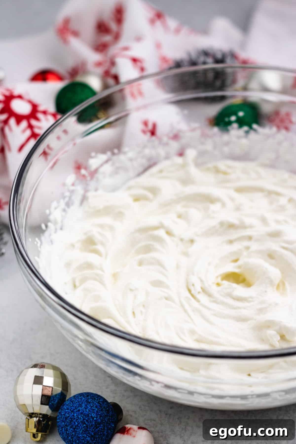 Beautifully whipped homemade cream, light and airy, filling a clear glass bowl, ready to top the pie.