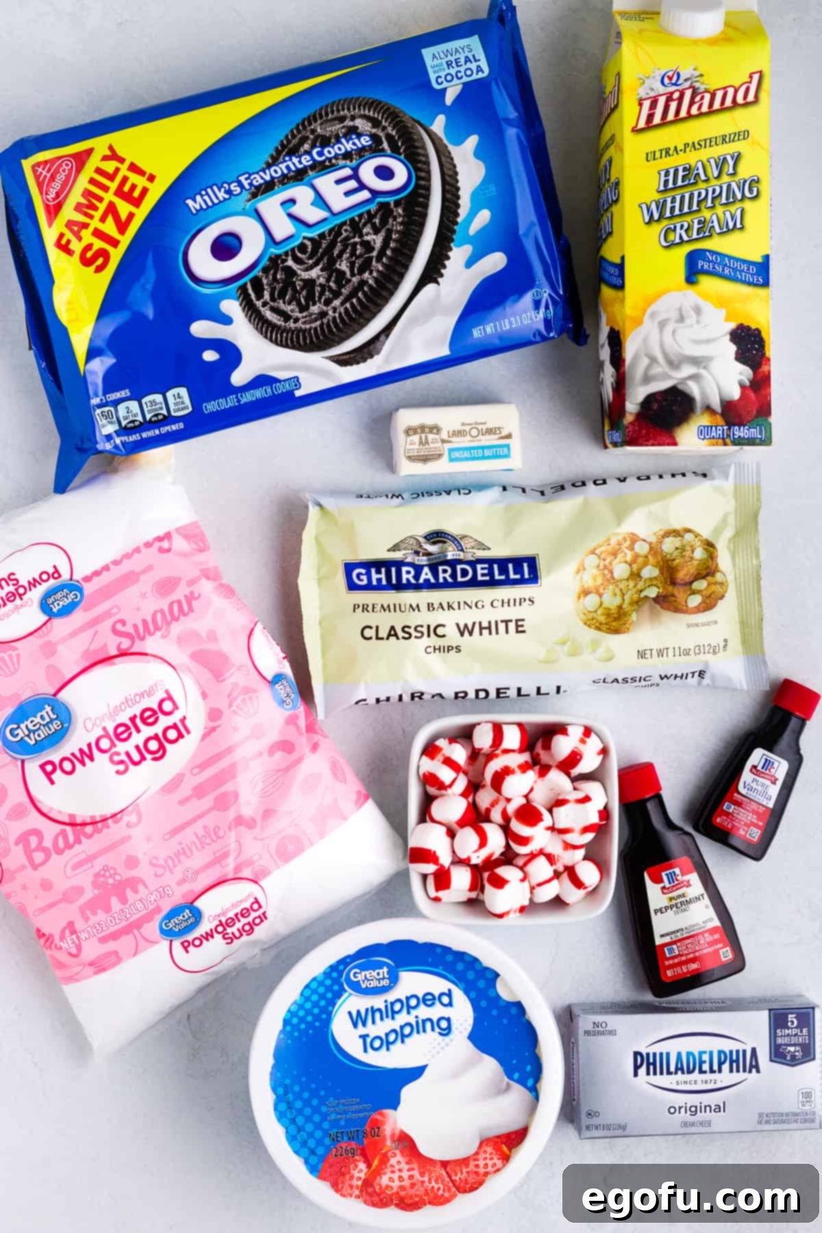 A vibrant flat lay of key ingredients for White Chocolate Peppermint Pie, including Oreo cookies, unsalted butter, cream cheese, white chocolate chips, peppermint extract, and a container of Cool Whip.