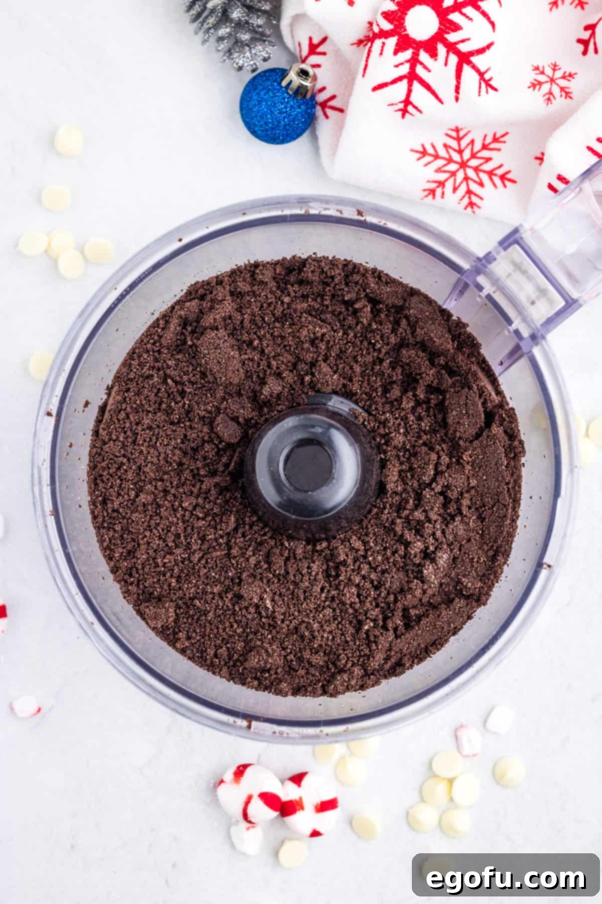 Finely crushed Oreo cookies covering the bottom of a food processor, demonstrating the ideal crumb consistency for a pie crust.