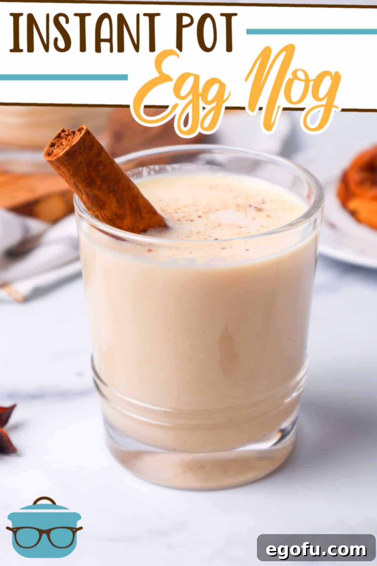 Instant Pot Egg Nog recipe from The Country Cook, pictured in a small glass with a cinnamon stick, shown on a marble surface.