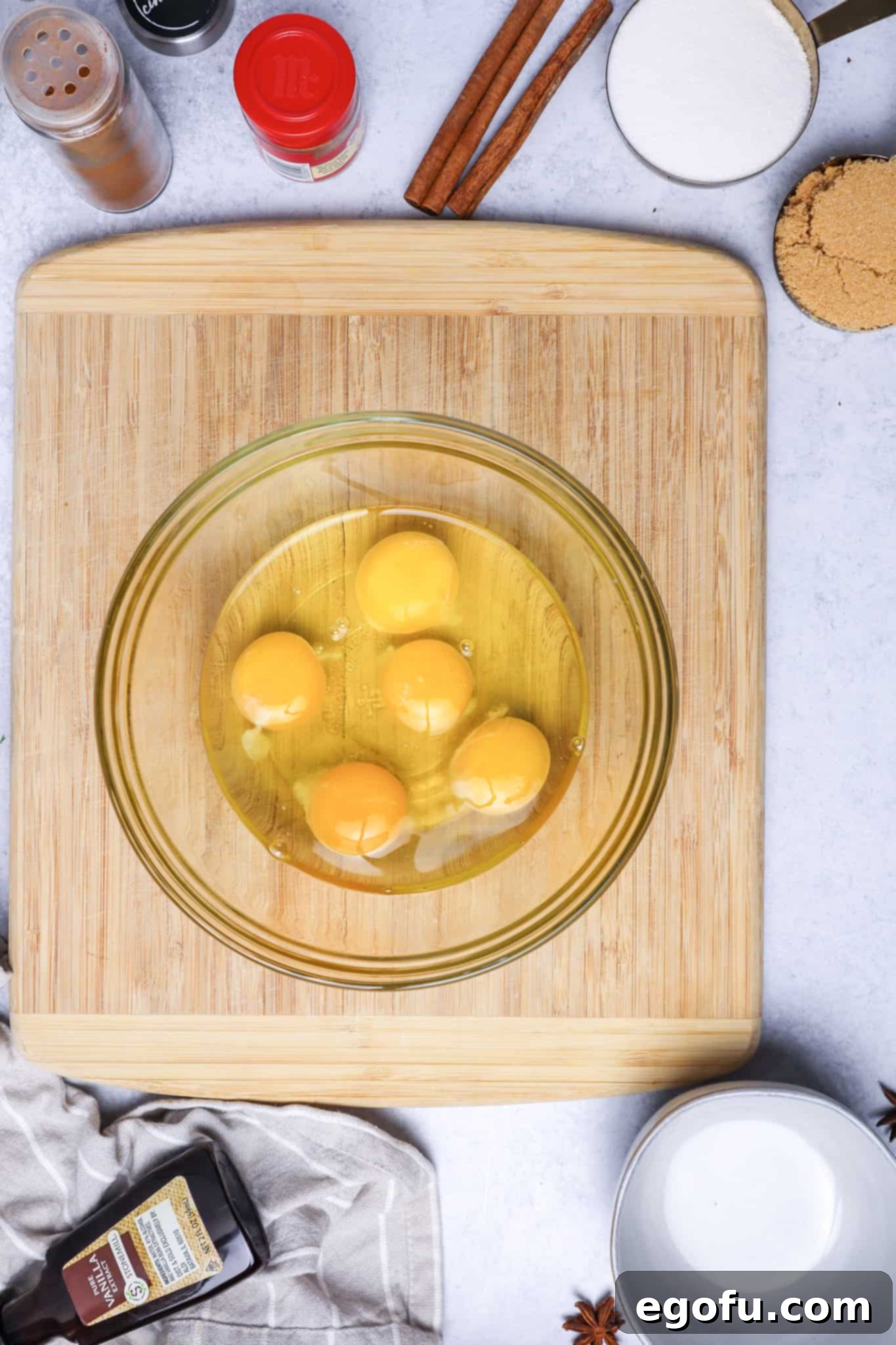 eggs in a clear glass bowl sitting on a wooden cutting board.