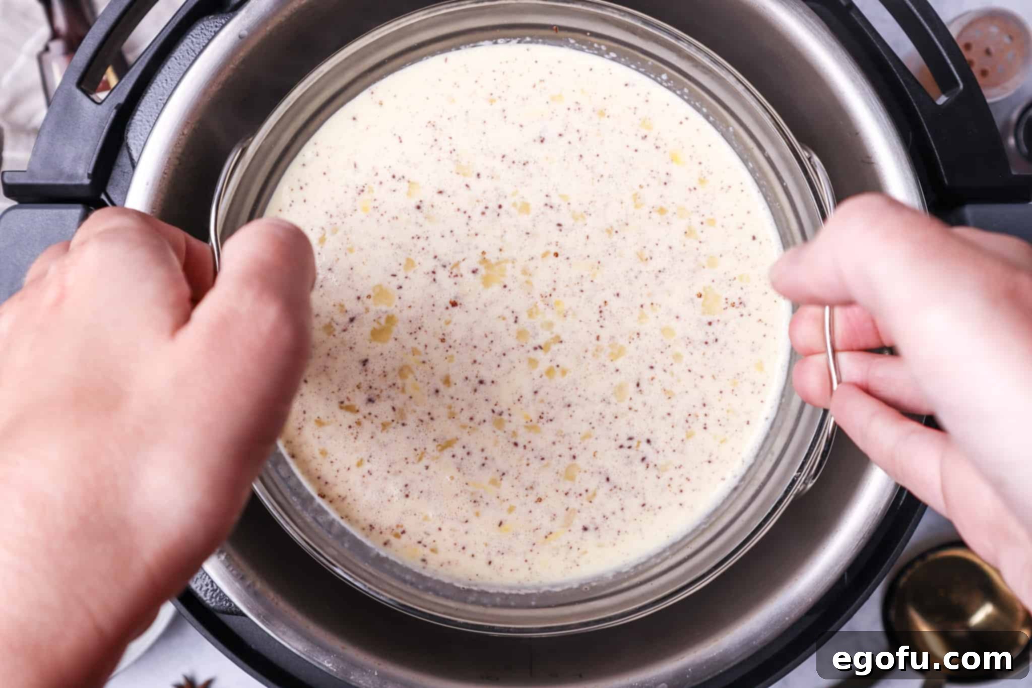 lowering bowl of egg nog mixture using a trivet into an electric pressure cooker.