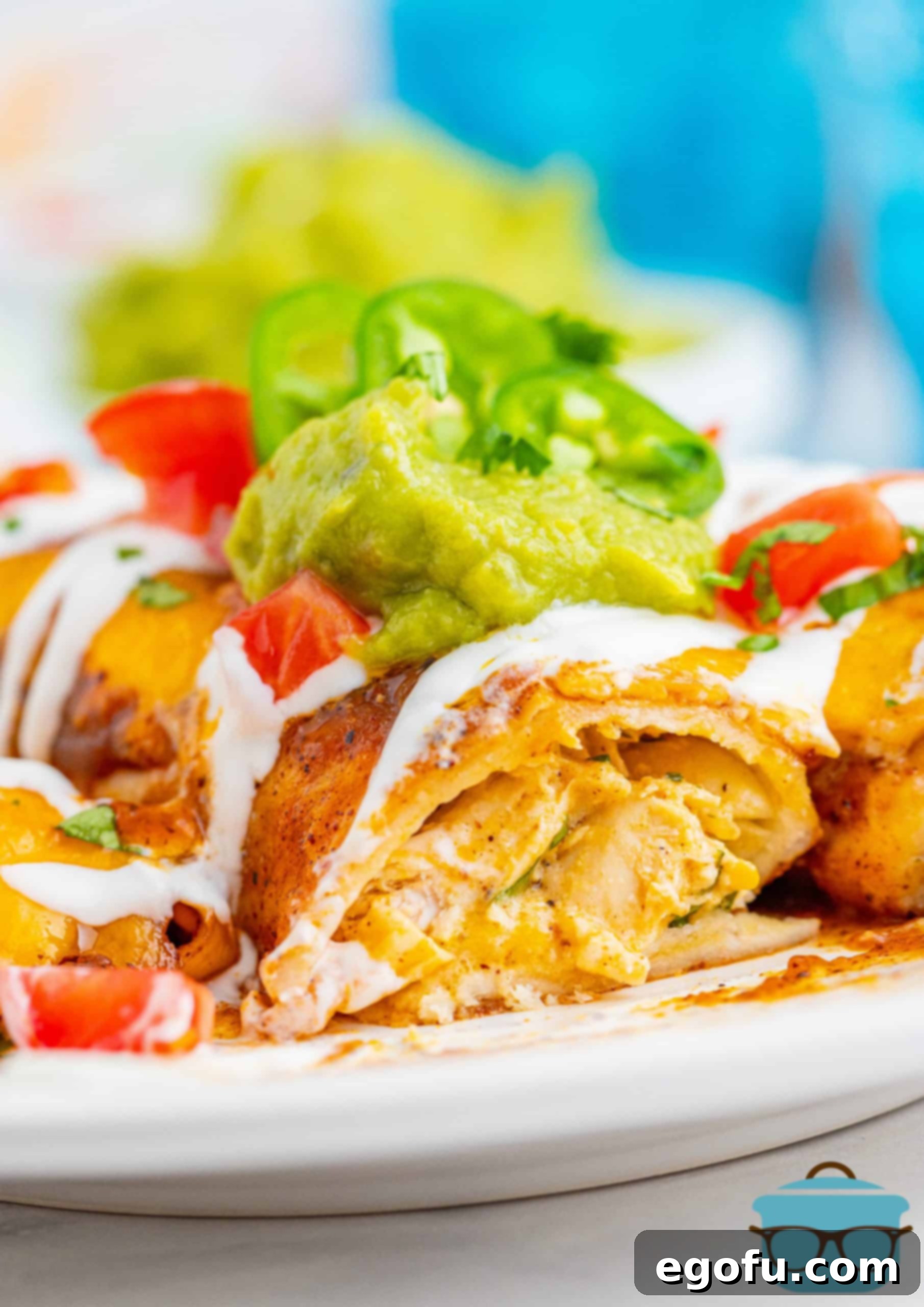 Photo showing the inside of a chicken enchilada with guacamole and cream sauce on top, highlighting the delicious filling and sauce.