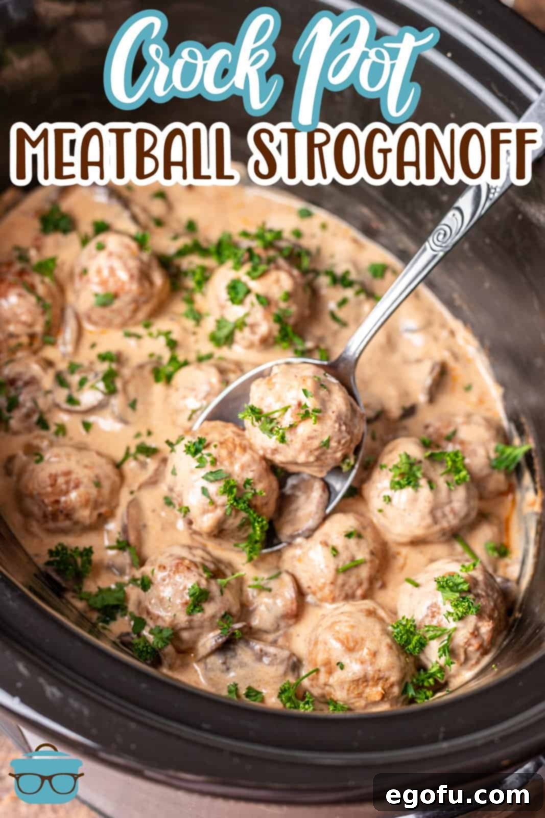 A silver spoon lifting two meatballs from a slow cooker filled with Crock Pot Meatball Stroganoff.