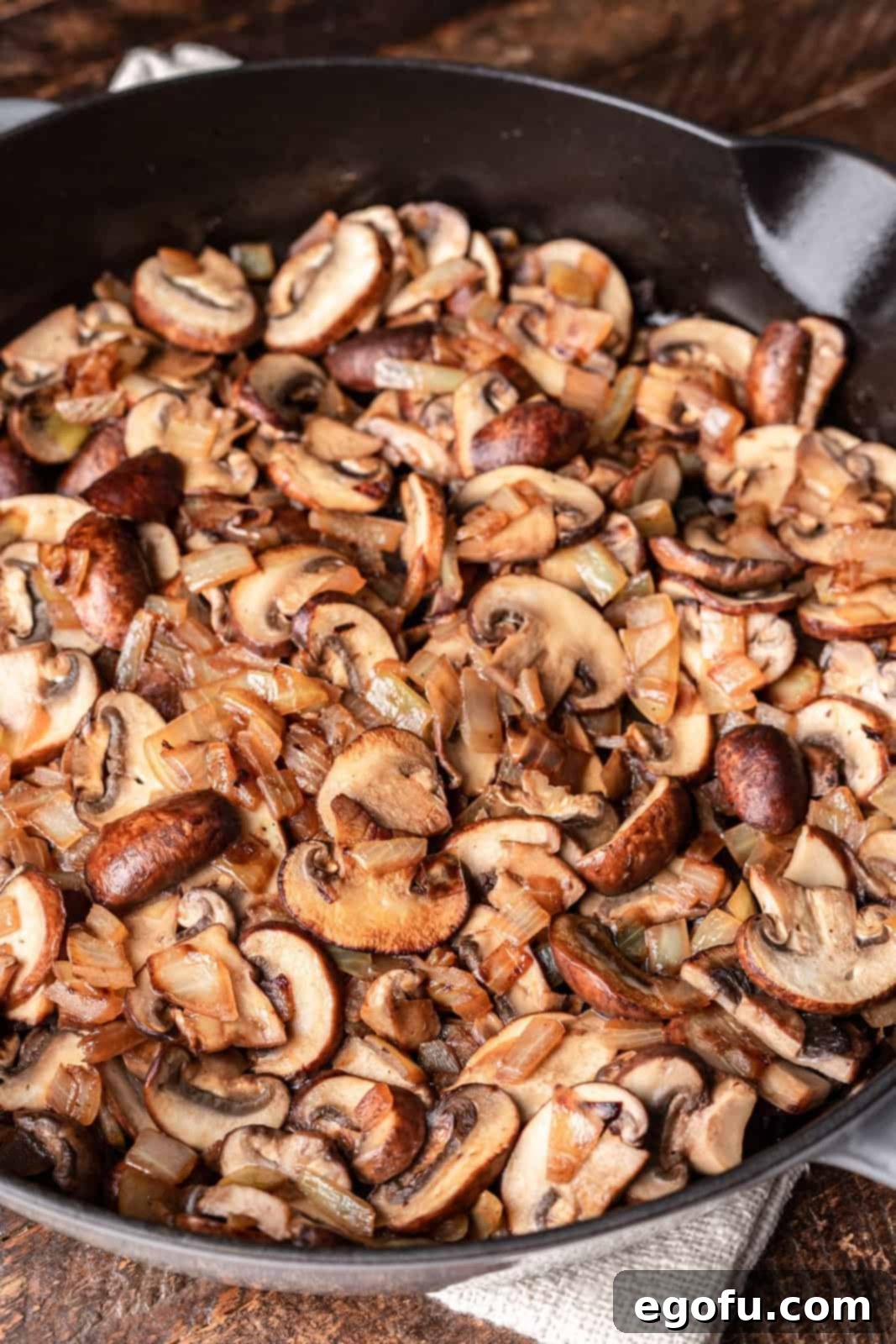Cooked, sliced mushrooms and onions in a skillet, lightly browned.