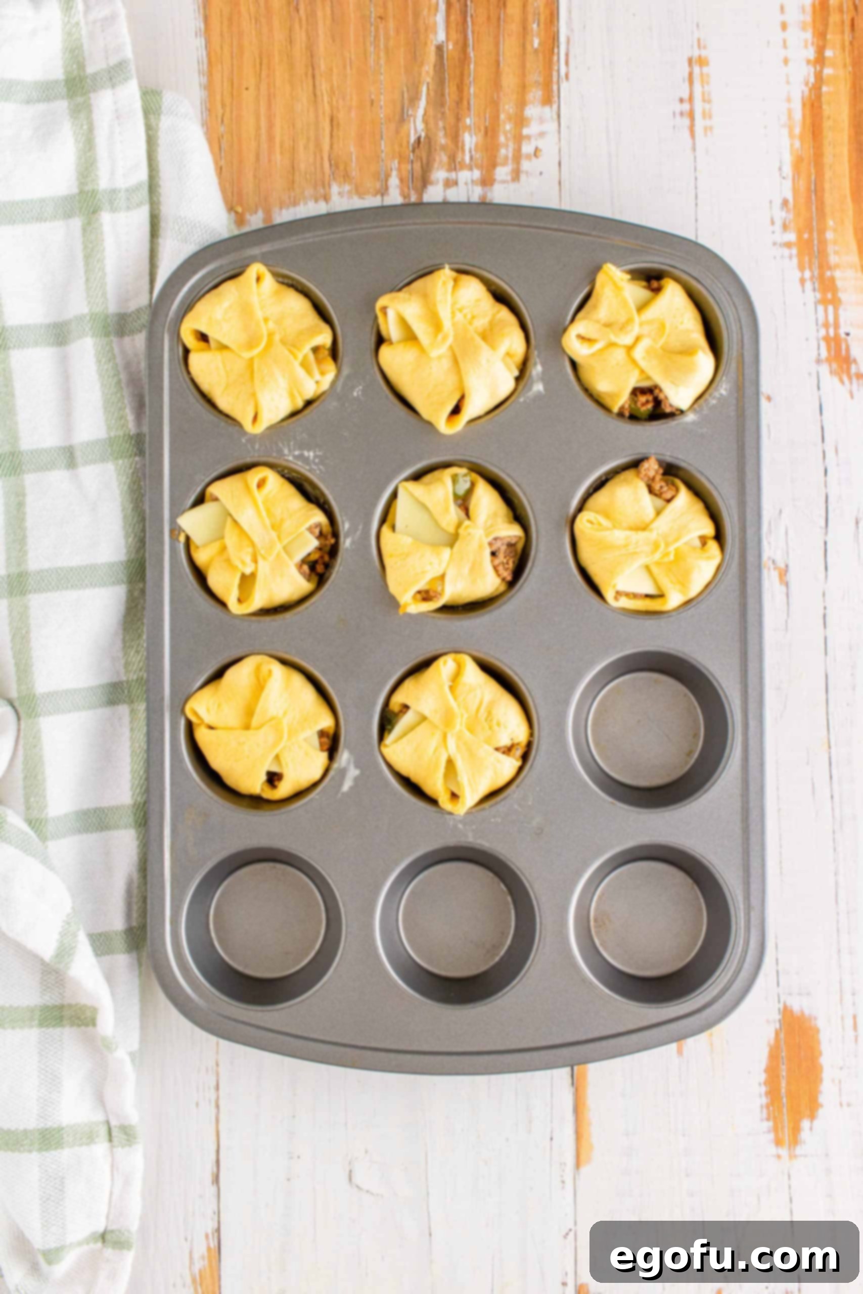 Philly Cheesesteak Poppers 11 Crescent dough squares sealed together in the muffin tin, forming closed cups.