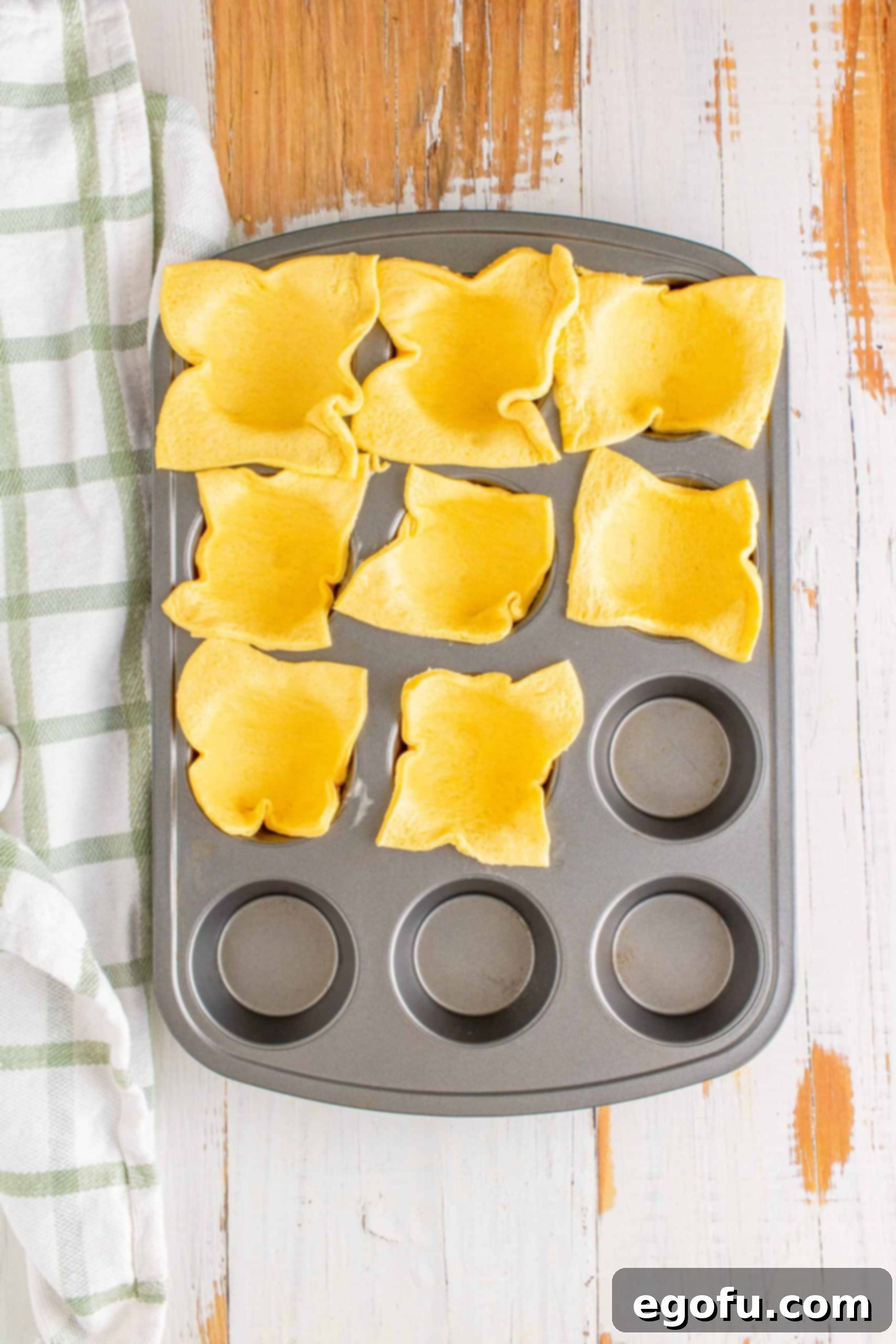 Philly Cheesesteak Poppers 7 Crescent dough squares pressed into a muffin tin.