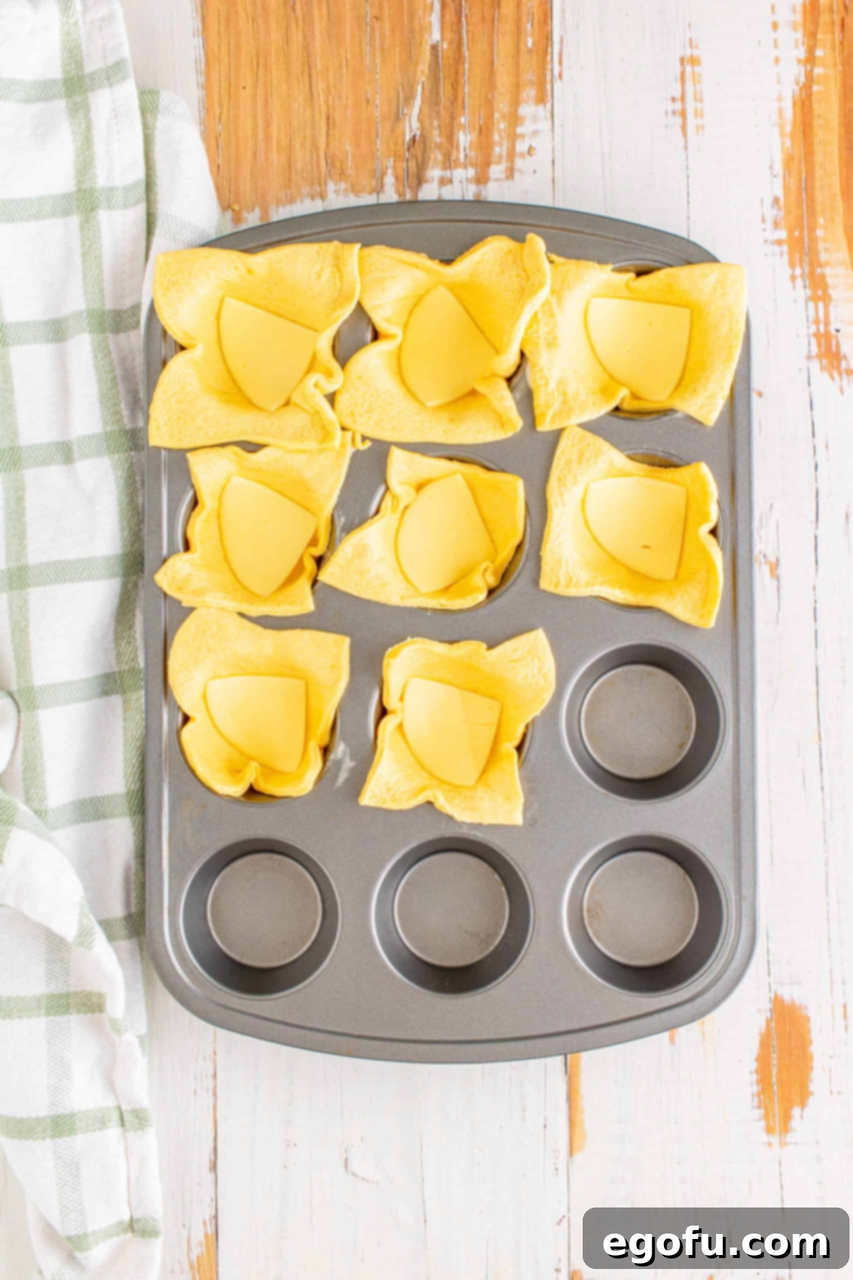 Philly Cheesesteak Poppers 8 Cheese pieces placed in the bottom of each dough square in the muffin tin.