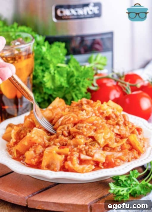 a serving of unstuffed cabbage rolls on a small round white plate with a fork inserted to the food.