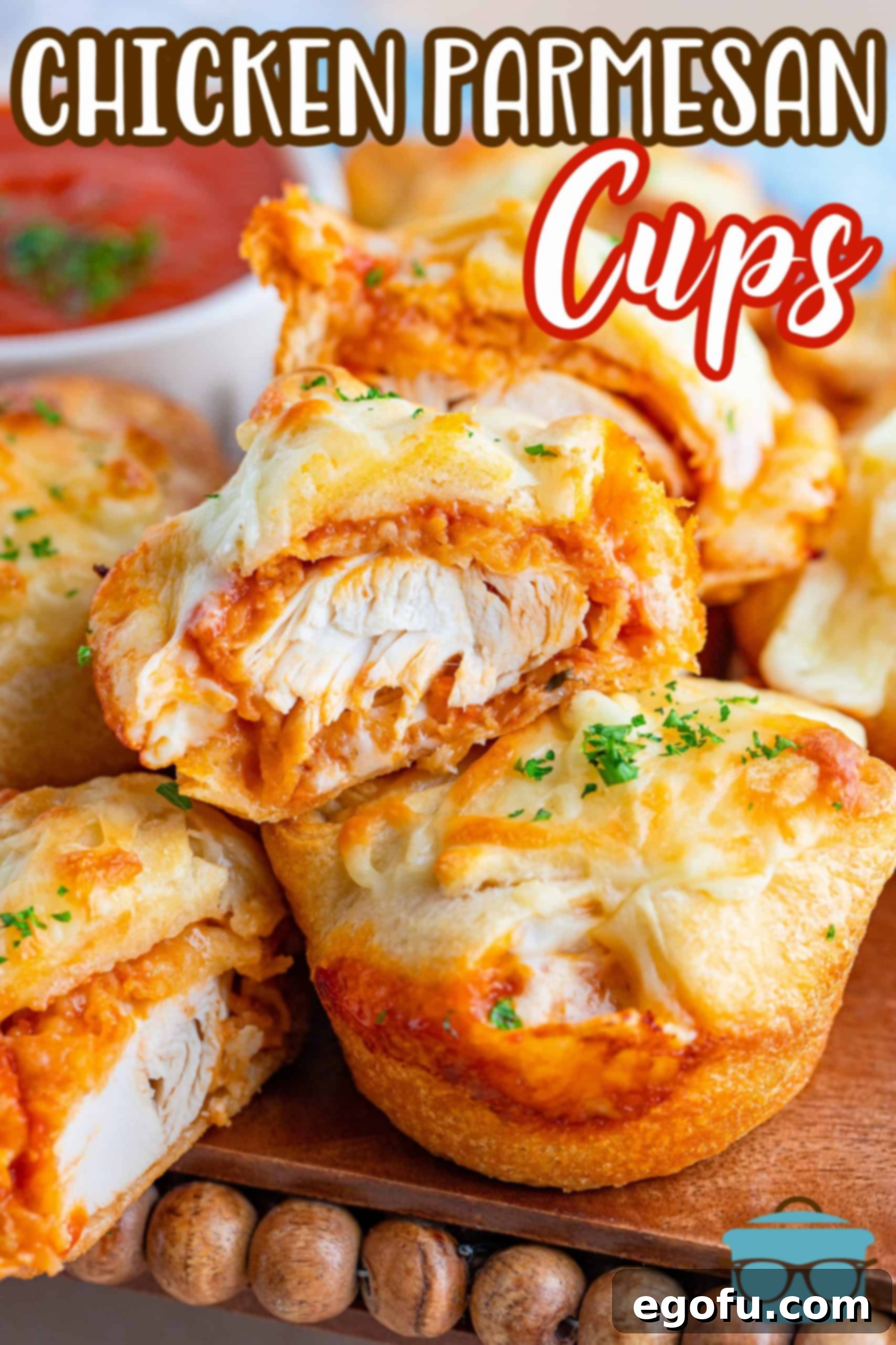 Two chicken parmesan cups stacked, one with a bite taken out, revealing the cheesy chicken and sauce filling inside the flaky crescent dough.