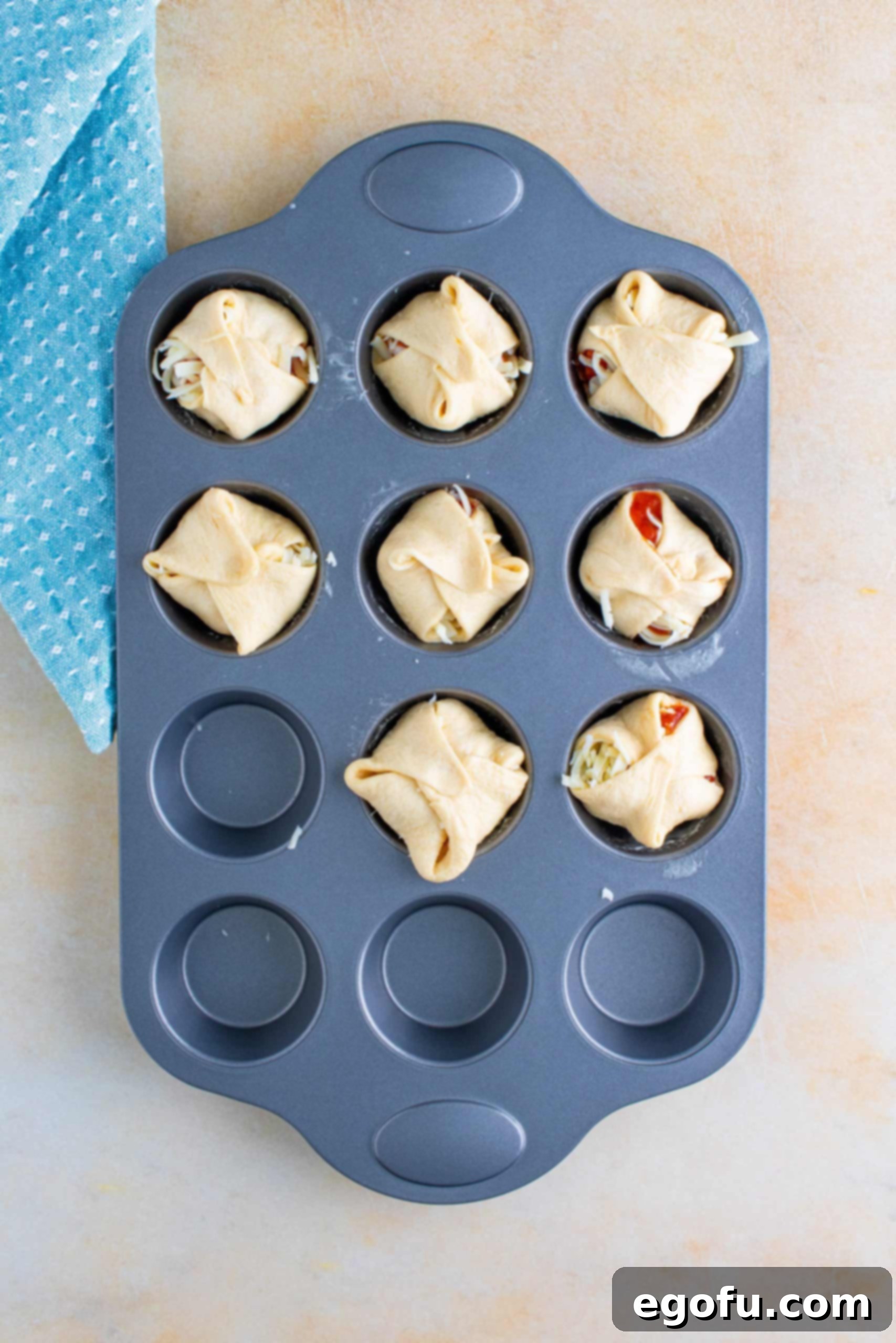 The corners of the crescent dough are folded over the chicken and cheese filling, creating a sealed cup.