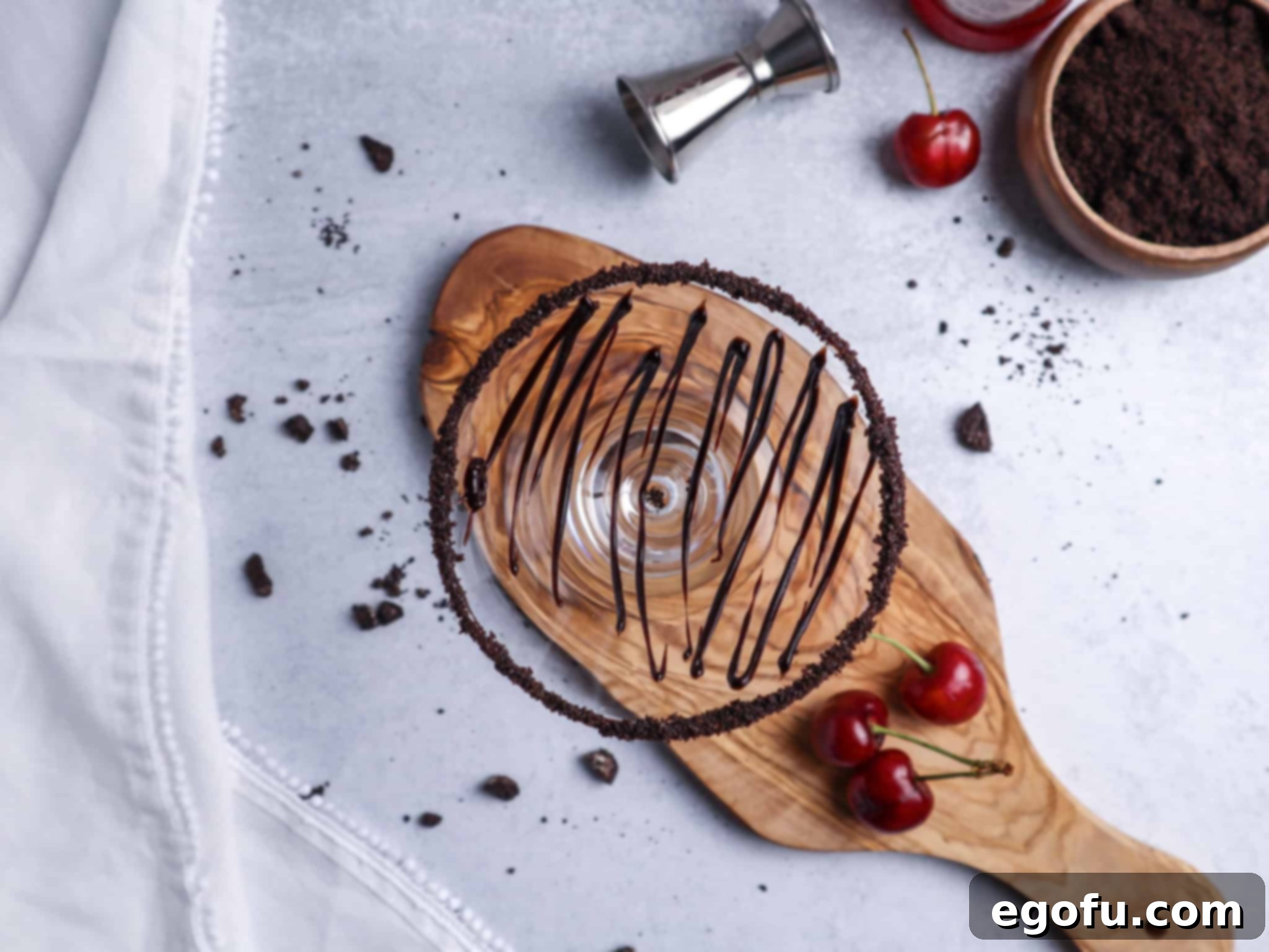 Martini glass dipped in chocolate syrup and crushed Oreos, with chocolate swirls applied to the inside of the glass, ready for the cocktail mixture.