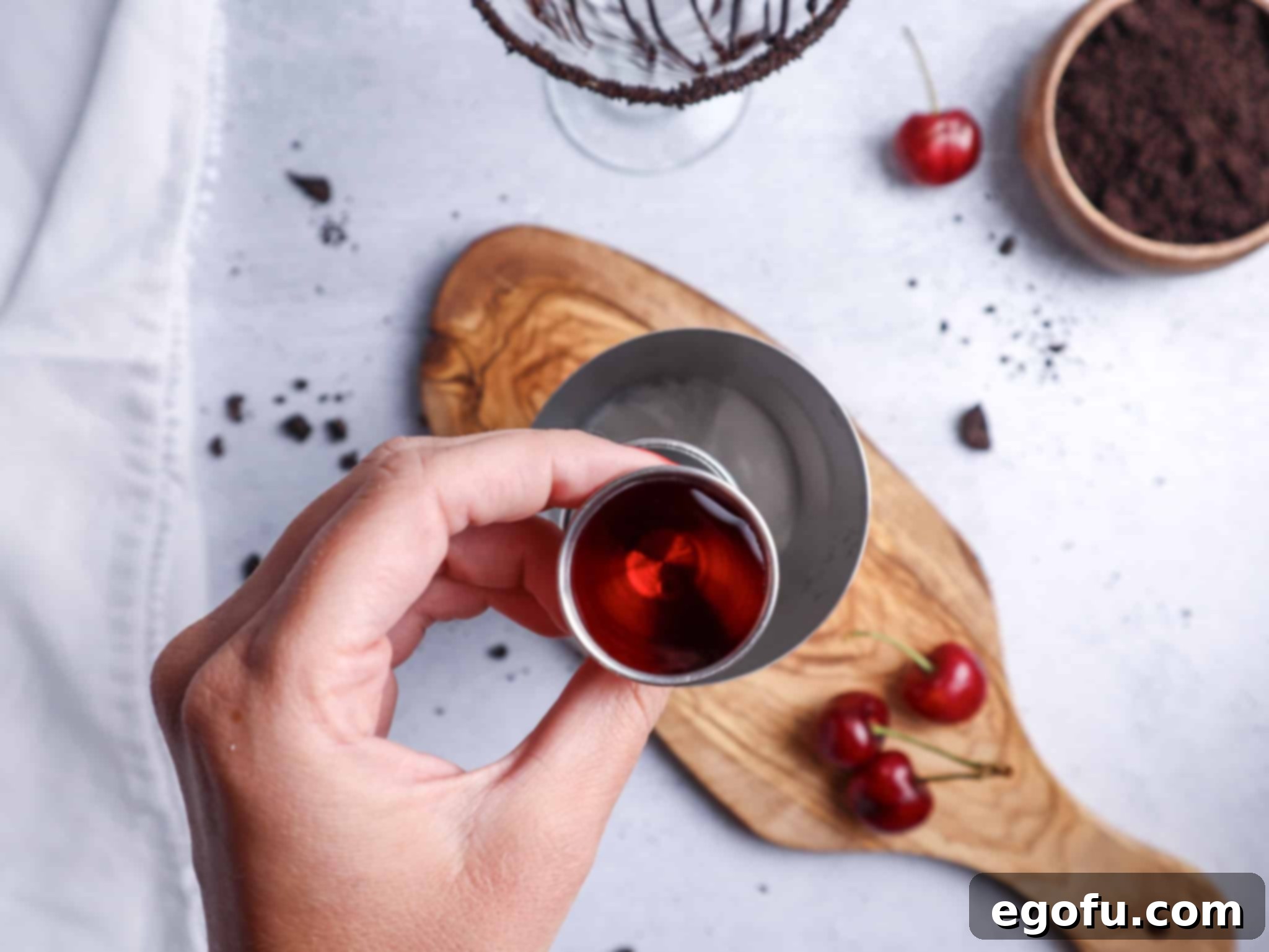 Grenadine measured precisely in a jigger, ready to be added to the cocktail shaker for color and sweetness.