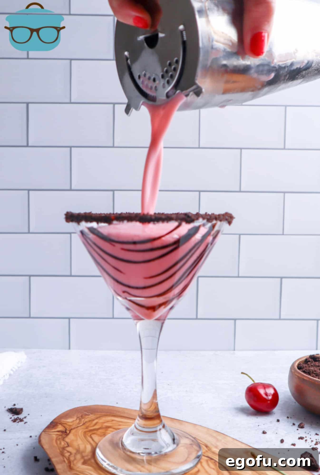 The cocktail shaker pouring the perfectly mixed Martini into the prepared glass, a crucial step in serving.