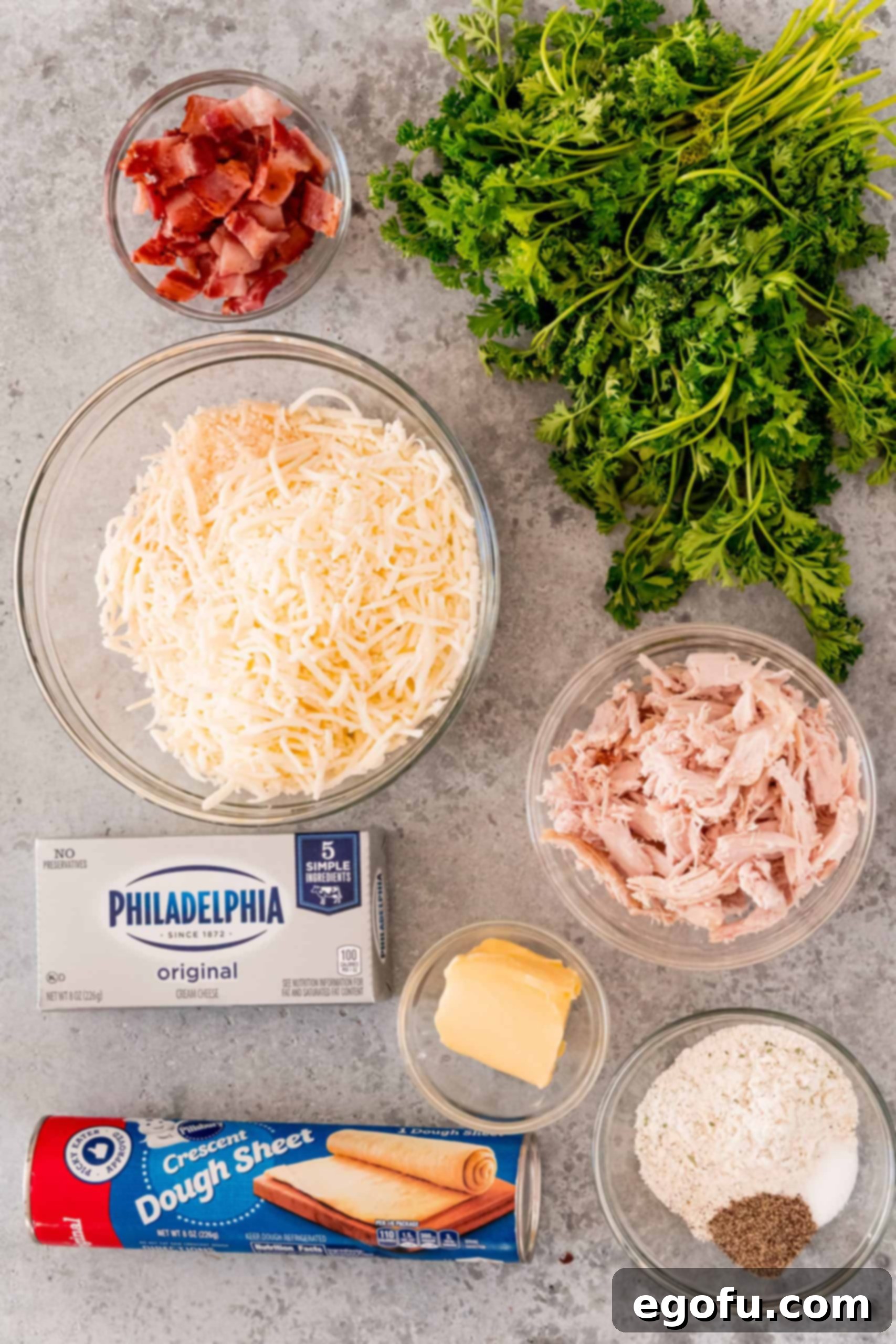 All the ingredients neatly laid out for making a Crack Chicken Ball: crescent roll sheet, diced cooked chicken, crispy bacon bits, softened cream cheese, shredded mozzarella, Parmesan cheese, ranch seasoning, melted butter, and fresh parsley.