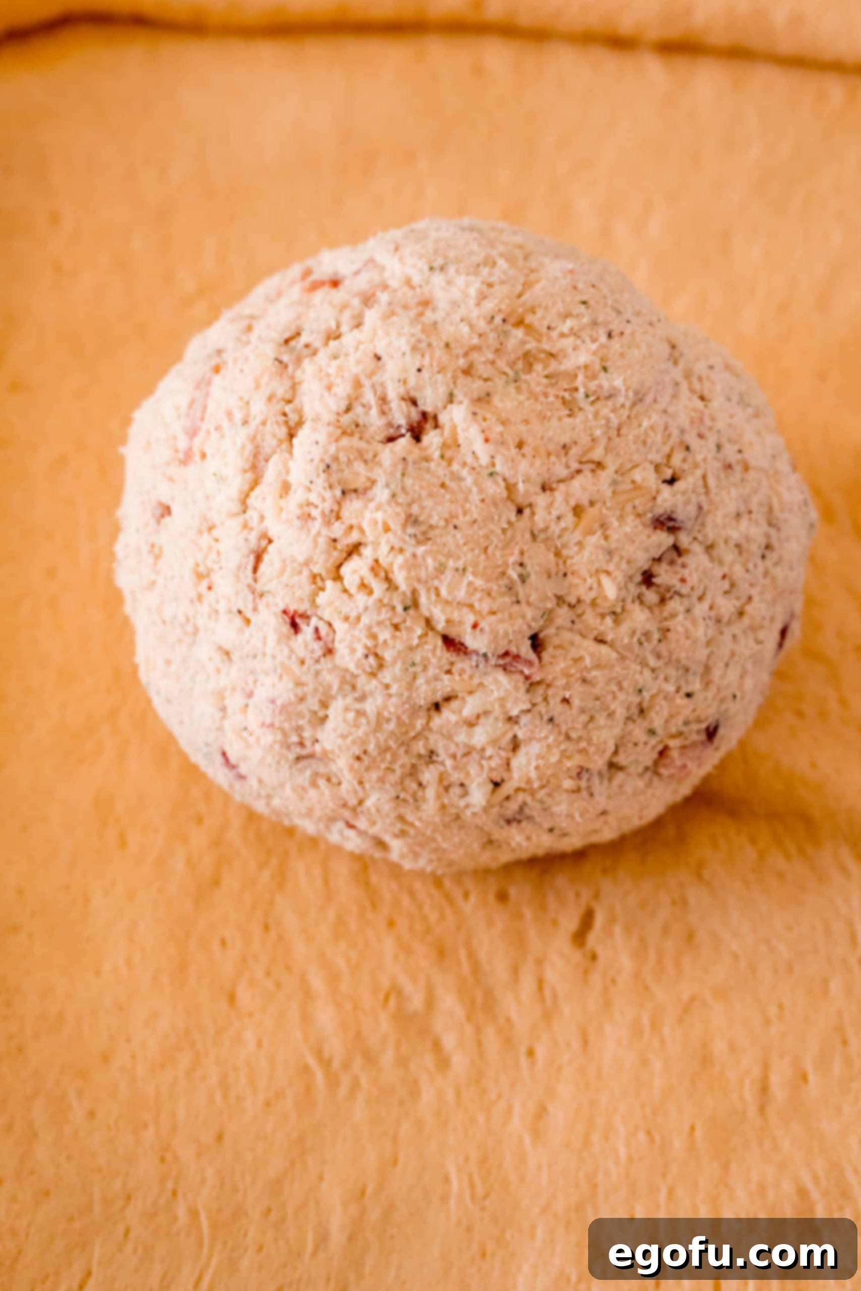 A neatly shaped ball of the crack chicken mixture placed directly in the center of an unrolled crescent dough sheet, ready for wrapping.